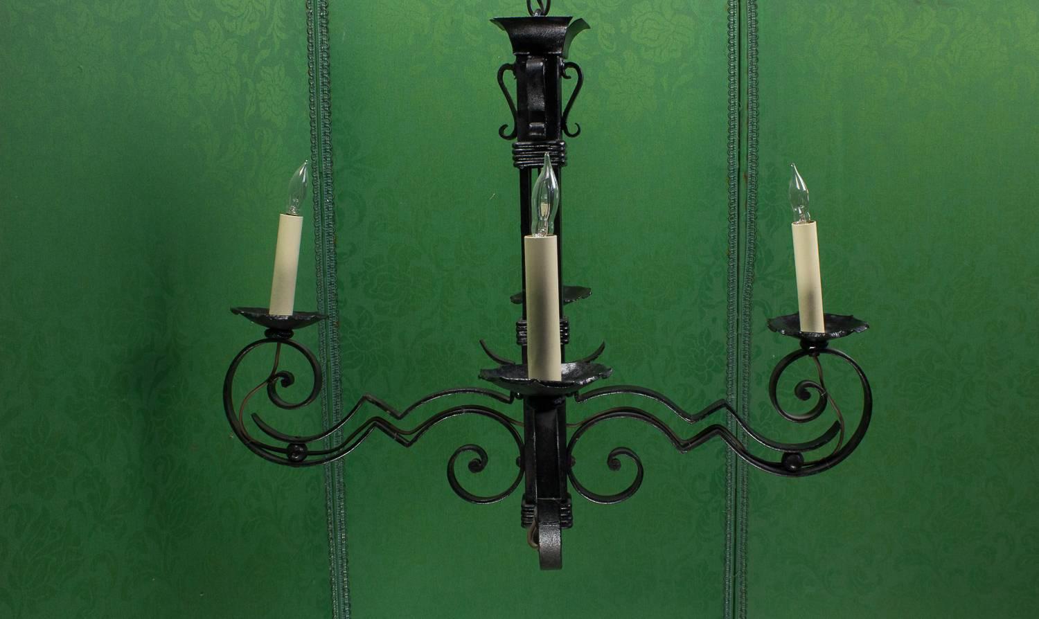 This French 1930s black iron chandelier is a unique piece that is sure to become the centerpiece of any room. Crafted in an Art Deco style, the chandelier boasts delicate intricate scrolled iron detailing, showcasing the craftsmanship and attention