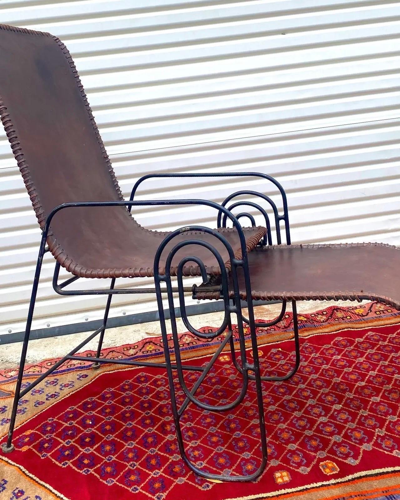 Art Deco leather and iron lounge chair with leather tied upholstery, wrought iron frame with pull-out foot rest; This chair definitely shows age but it is no doubt a stunning piece of art and remains very sturdy. This chair is more than once