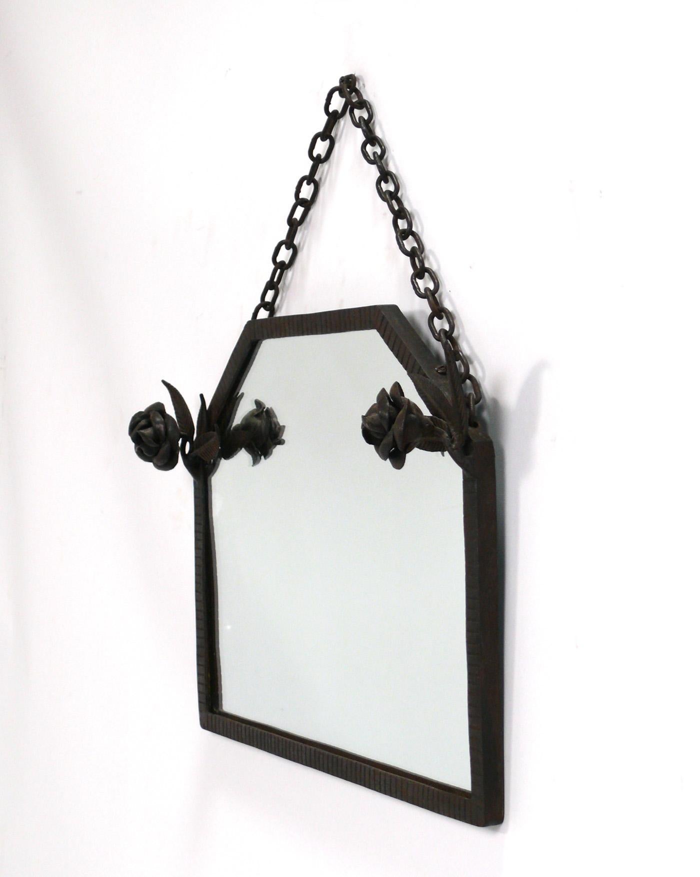 Elegant French Art Deco hand made iron mirror, France, circa 1930s. Beautiful hand hammered iron work surmounted with roses. The mirror glass has been replaced at some point.
