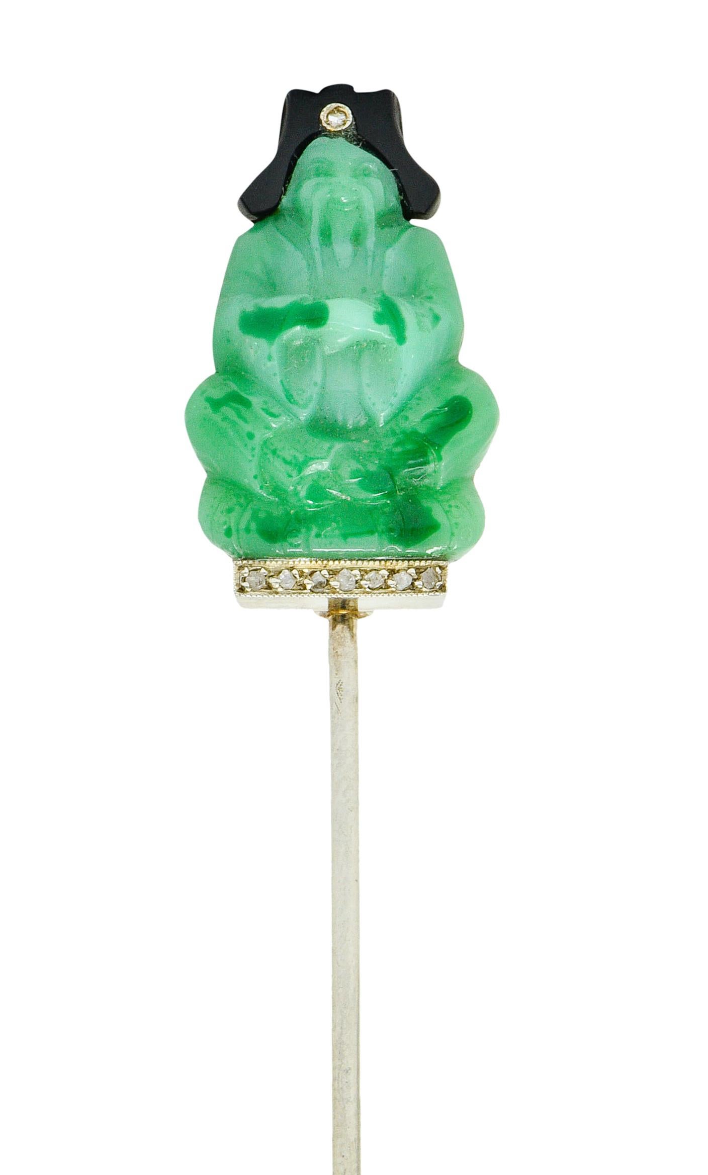 Jabot stickpin features deeply carved jade that depicts a seated and mustached emperor

Jade is semi-opaque and a light pastel green color with unique dark green areas of mottling

Topped by an onyx headdress, opaque and lustrous black

With