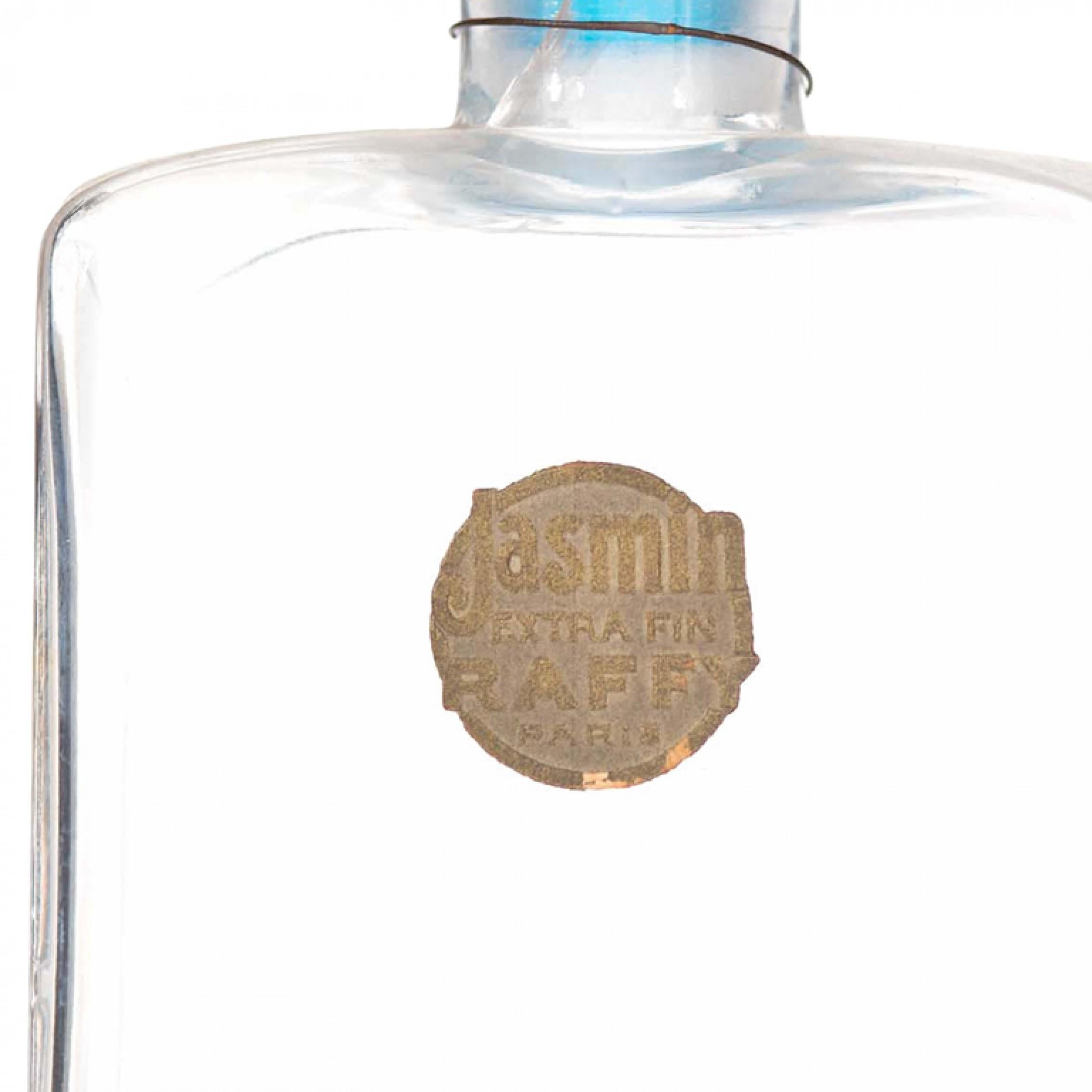 Bottiglia di profumo rettangolare in vetro trasparente Art Deco francese (JASMIN by RAFFY) con tappo in vetro smerigliato colorato blu in rilievo.