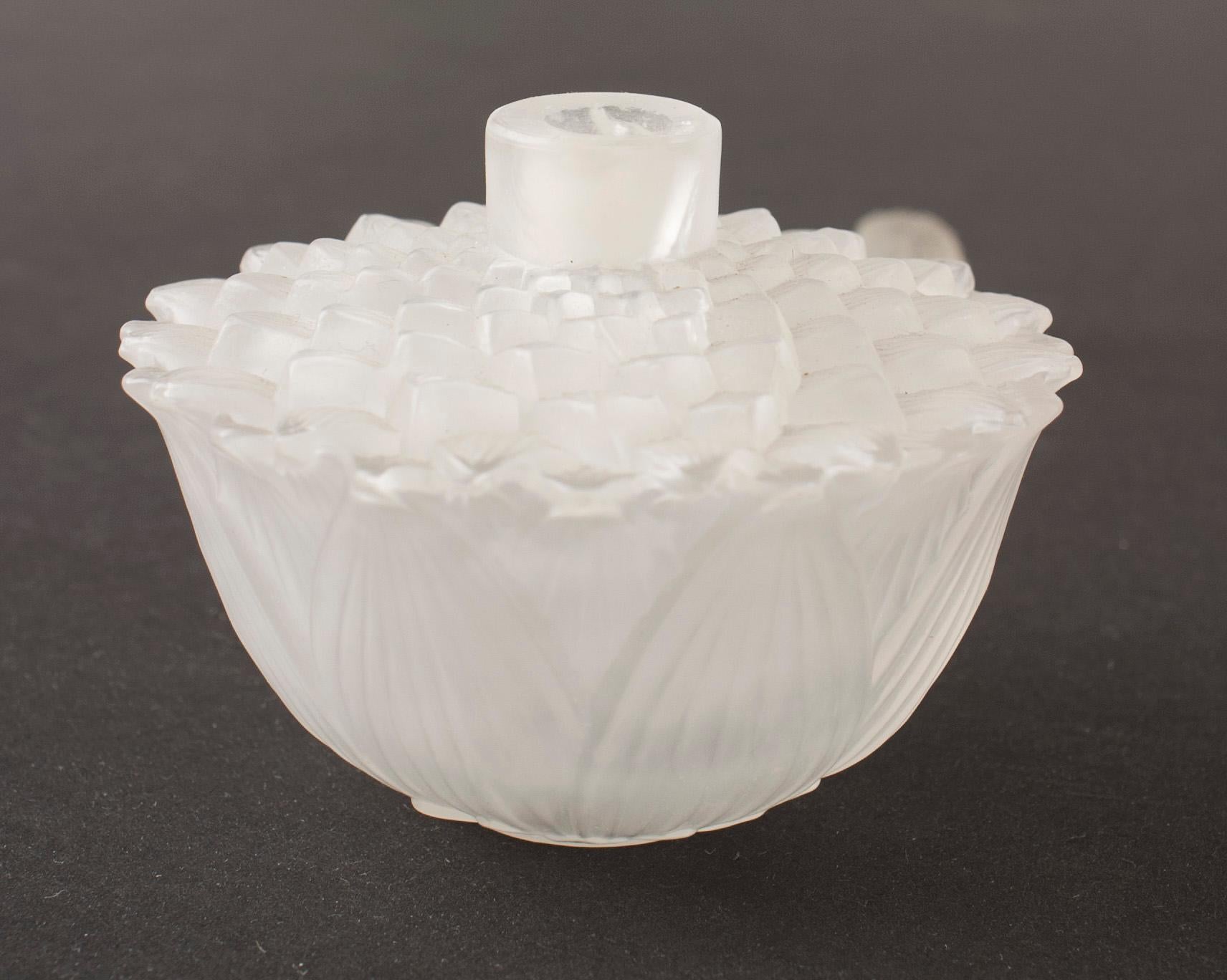 French Art Deco flower-shaped glass perfume bottle with molded lotus style petals around the exterior and a dome-shaped stopper (signed Lalique) (as is- crack on neck).
 