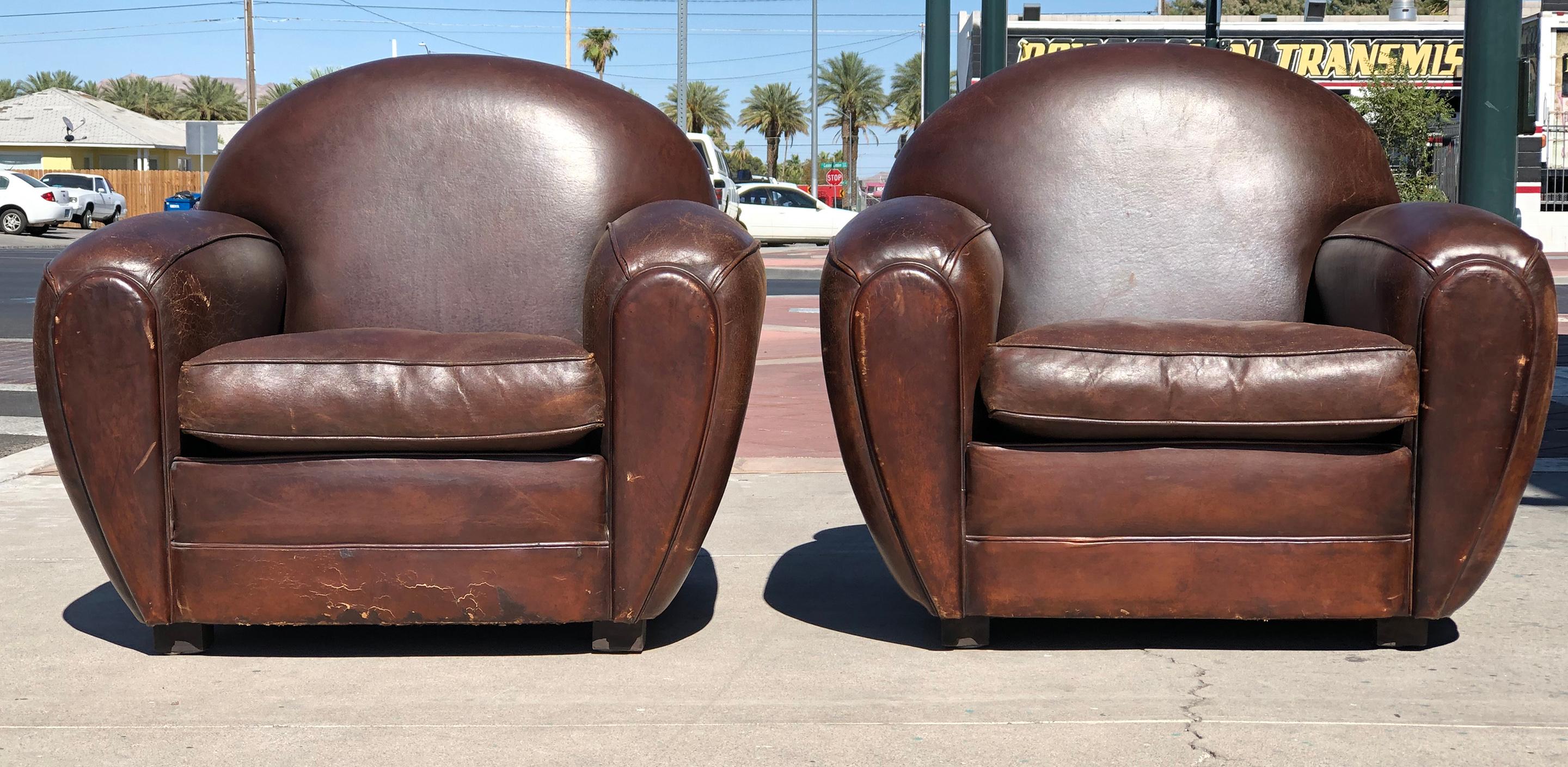 An absolutely fabulous pair of round Art Deco leather club chairs. These leather club chairs were purchased in the 1980's in Paris at the Les Puces de Saint-Ouen. The chairs were re-dyed about 4 years ago and are in stunningly distressed condition