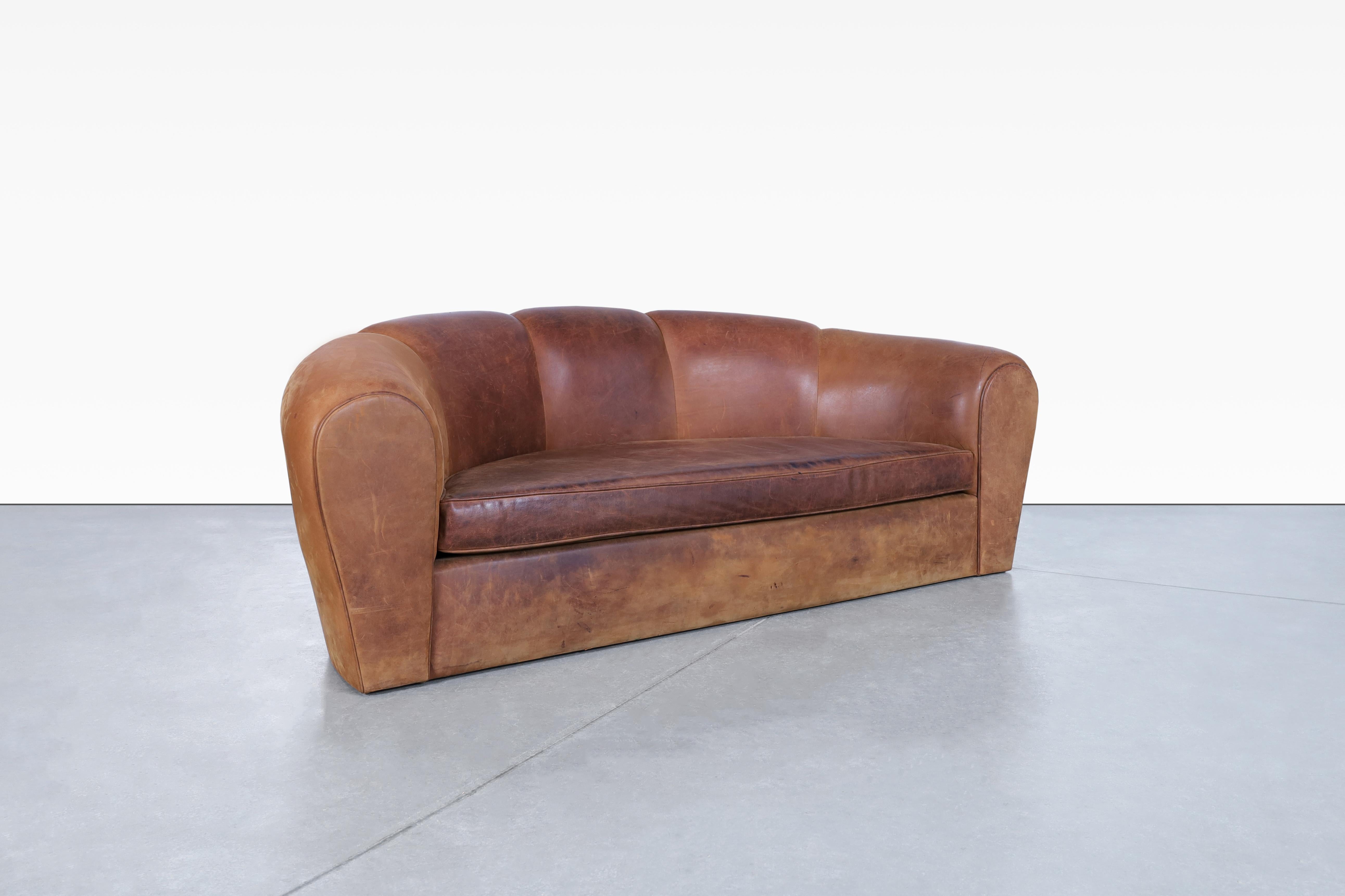 Stunning French art deco leather “Croissant” sofa manufactured in France, circa 1980s. This sofa, adorned in rich brown leather, exudes a sense of elegance. The sturdy construction ensures its durability, promising years of comfort and style. The