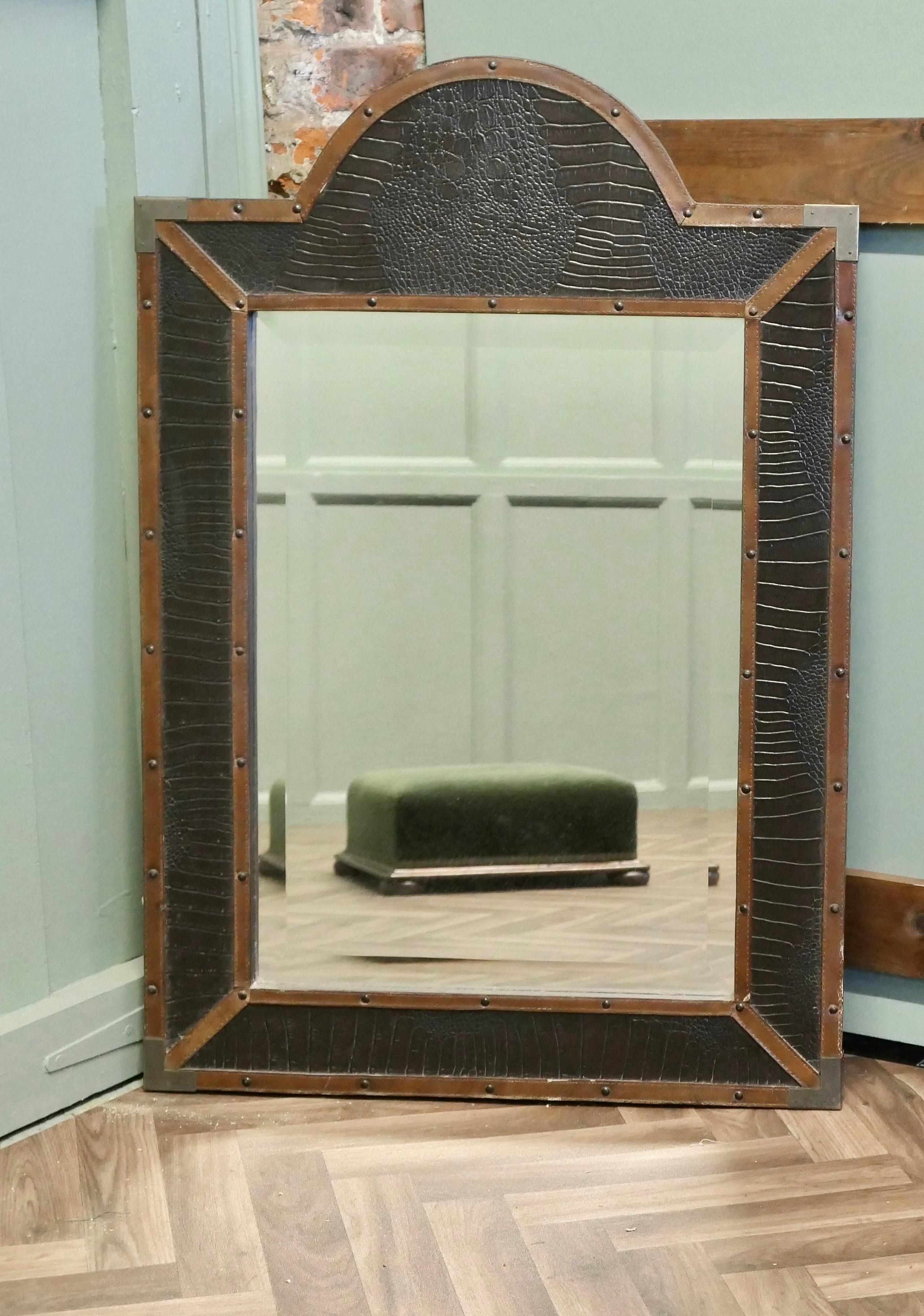 French Art Deco Leather Wall Mirror

A very unusual piece, the mirror has a wide bevelled edge and is set in an arch top frame which is covered with leather and it has brass corners in the campaign style 
The piece is in good condition it is 28”