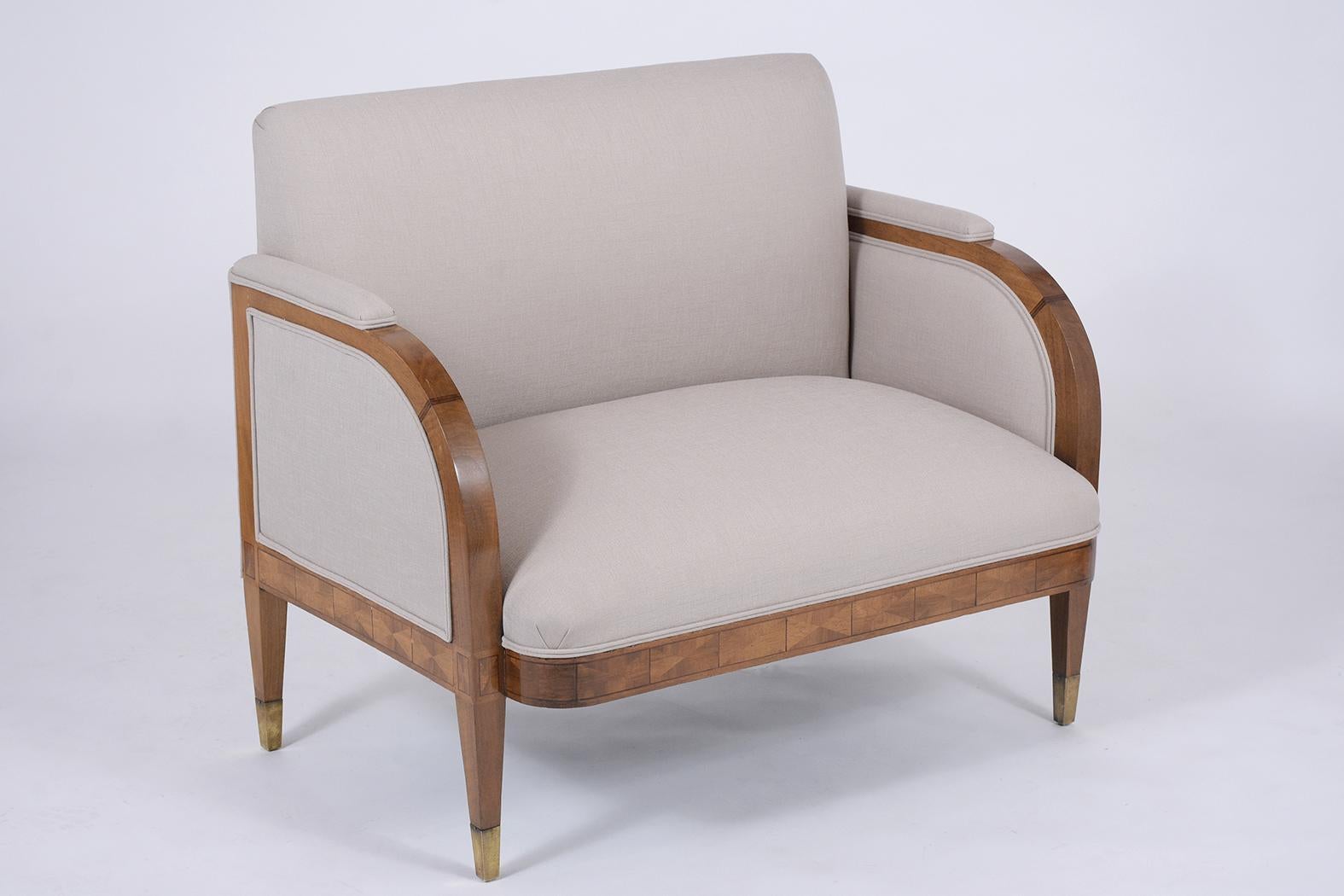 A French Art Deco loveseat handcrafted out of wood this elegant loveseat features a walnut finish. Eye-catching inlaid details arched armrests. This fabulous piece sits on carved tapered legs with brass toe cups a comfortable seat and a backrest