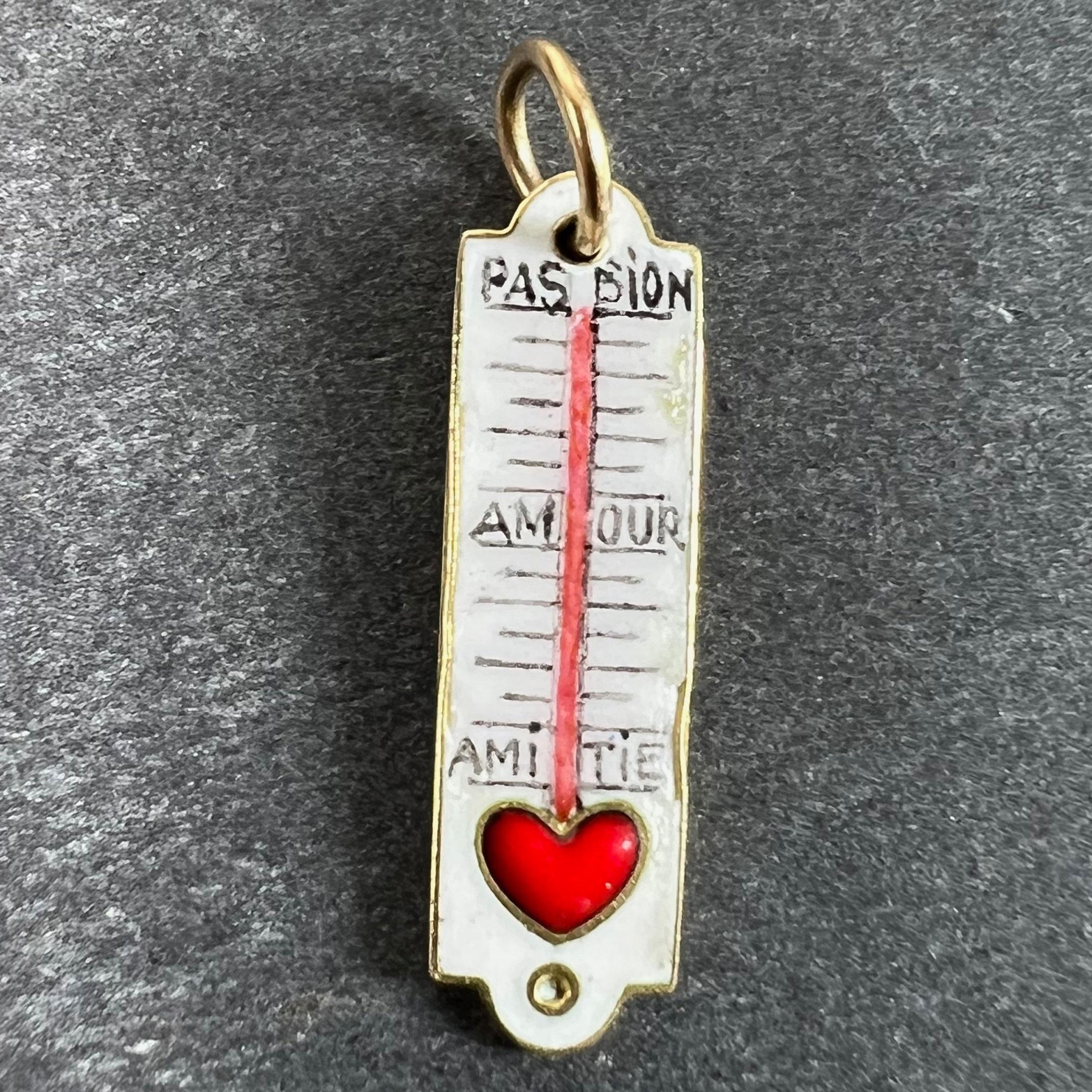 A French Art Deco 18 karat (18K) yellow gold charm pendant designed as a thermometer of love, set with white, red and black enamel to show a red love heart at the base with the temperature rising from 'Amitie' (friendship), through 'Amour' (love)