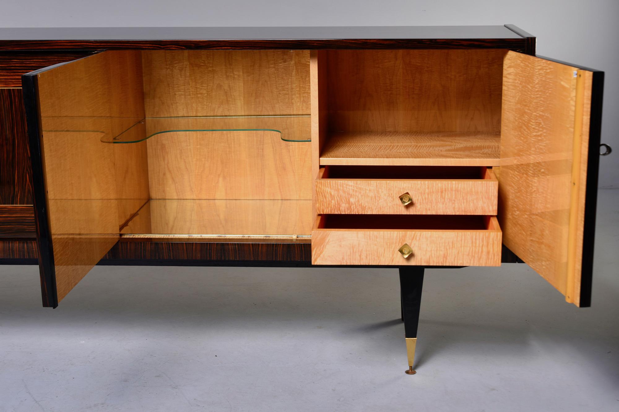 French Art Deco buffet or credenza in Macassar, circa 1940s. Cabinet front features elaborate geometric marquetry. Locking cabinets on each end with drawers top on one side with open storage above. The middle compartment features a glass shelf next
