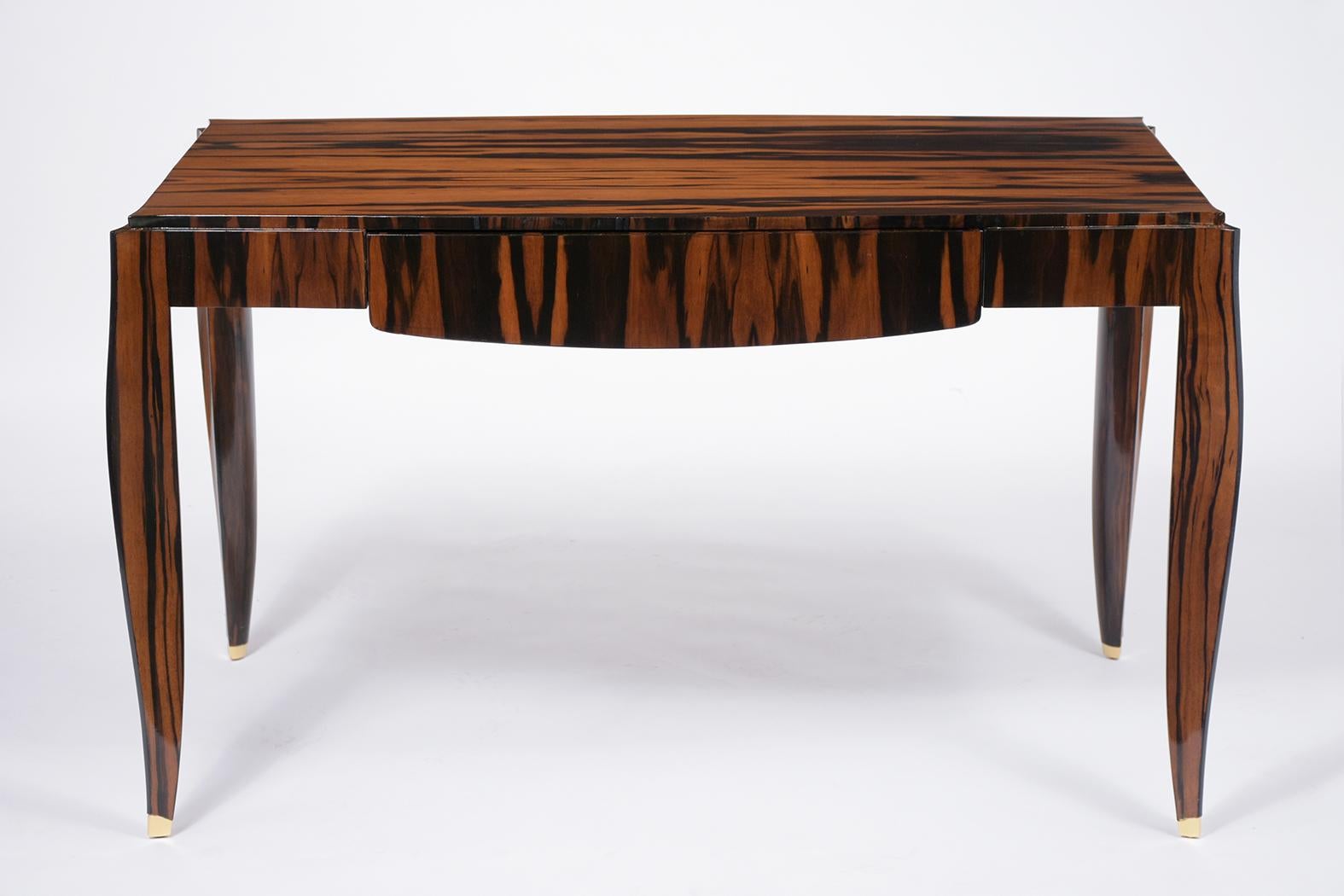 An elegant vintage Art Deco desk handcrafted out of mahogany in the style of Émile-Jacques Ruhlmann covered in a Macassar veneer and is fully restored. This writing table features a rich mahogany color stain with a newly lacquered finish and comes