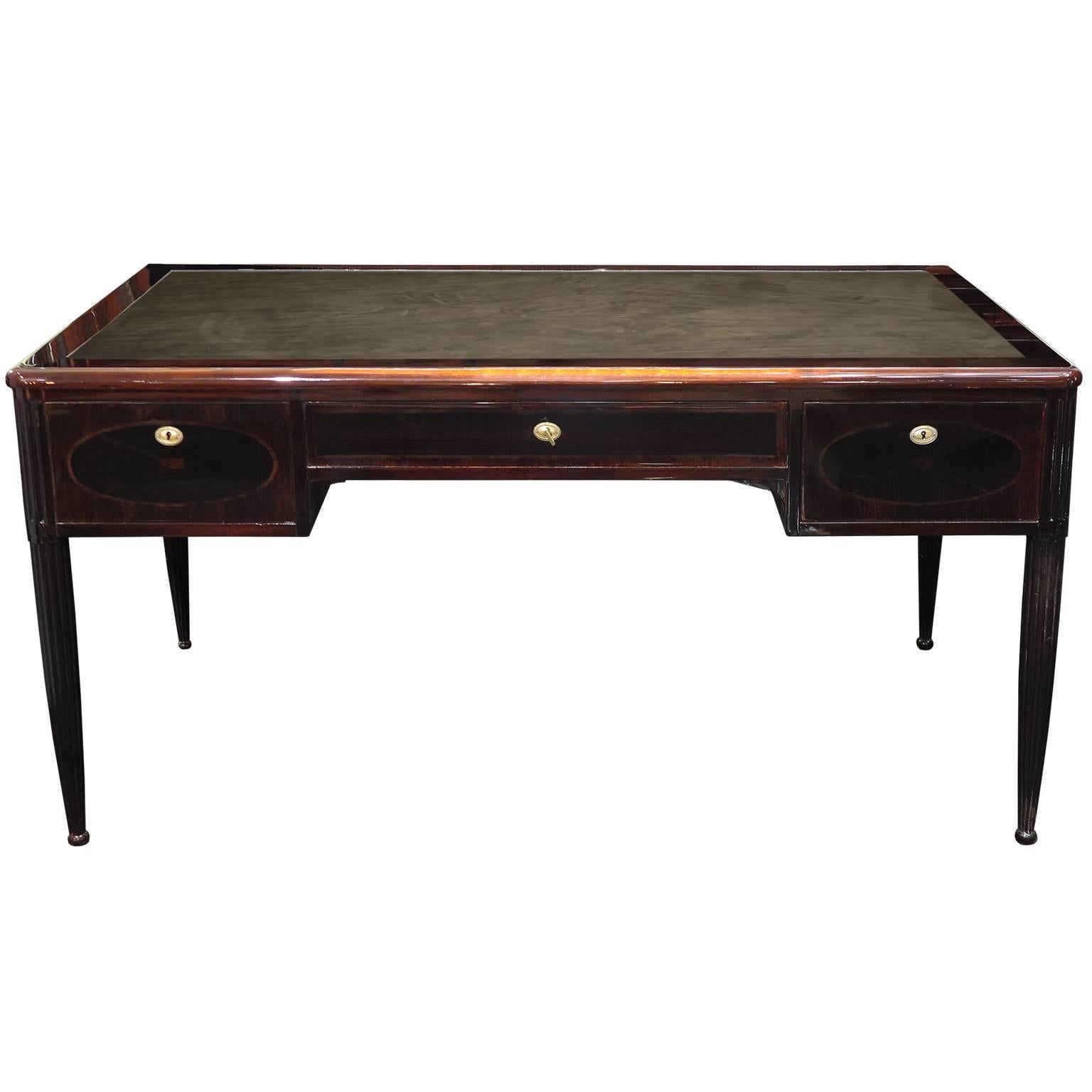 Beautiful Macassar ebony and mahogany desk. Desk has Macassar marquetry inlays on front and back drawers. Desktop and side shelves are covered in black suede. The side shelves extend out to 15” each for additional surface space. Original brass