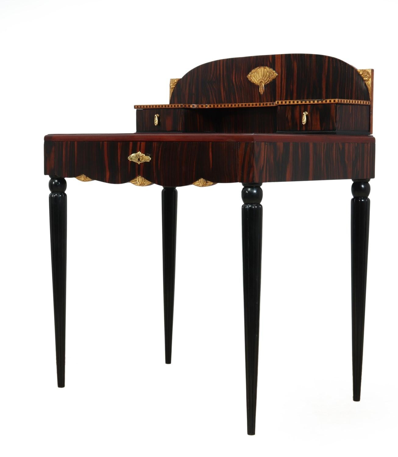 French Art Deco Macassar ebony and giltwood Bonheur du Jour

A bonheur du jour or ladies writing desk in Macassar ebony with gilt carving escutcheon and handles, ebonized legs that are tapered with reeded detail large central drawer that is