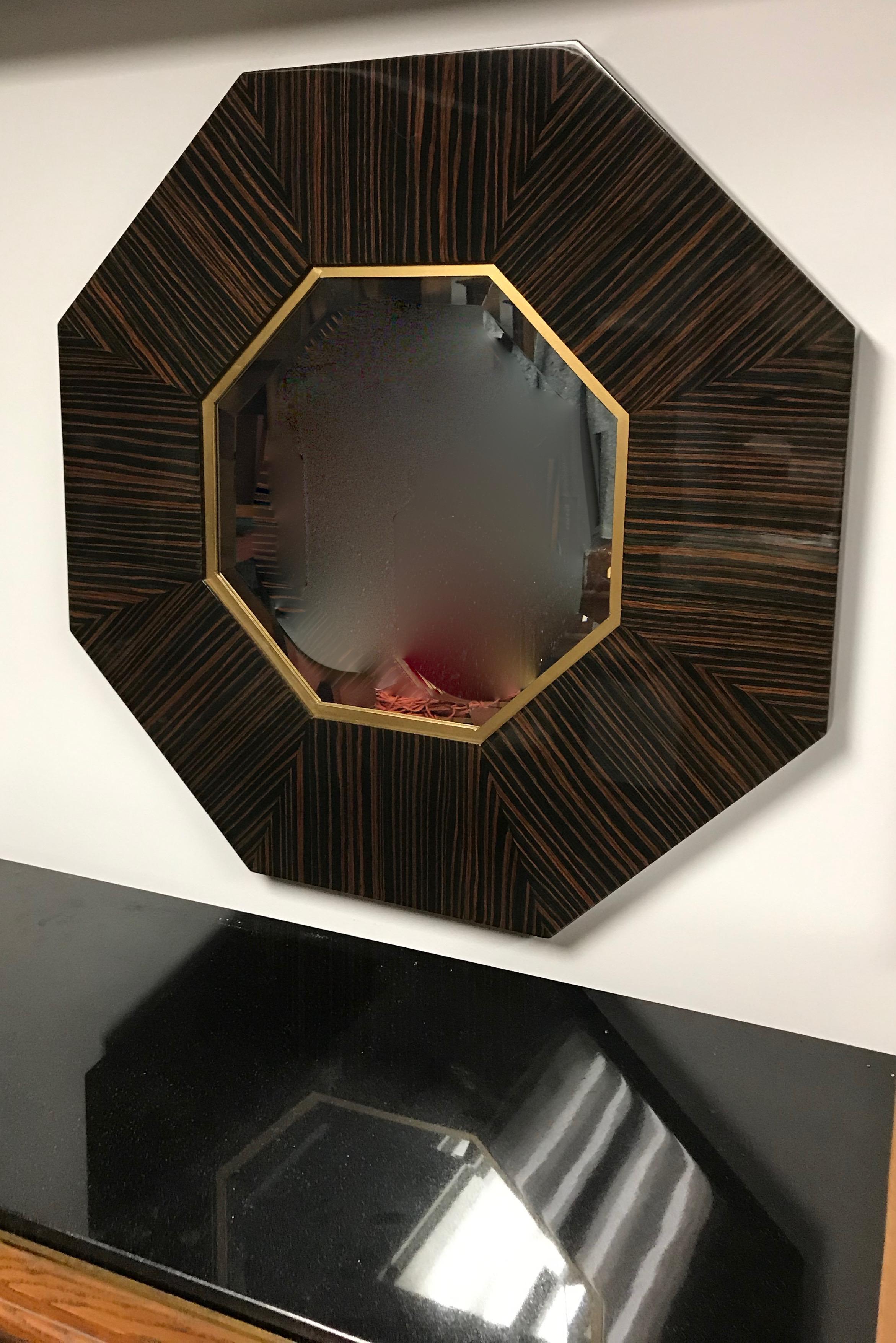 Stunning French Art Deco eight sided Macassar ebony hanging wall mirror. With beautiful beveled glass and brass accents. 
