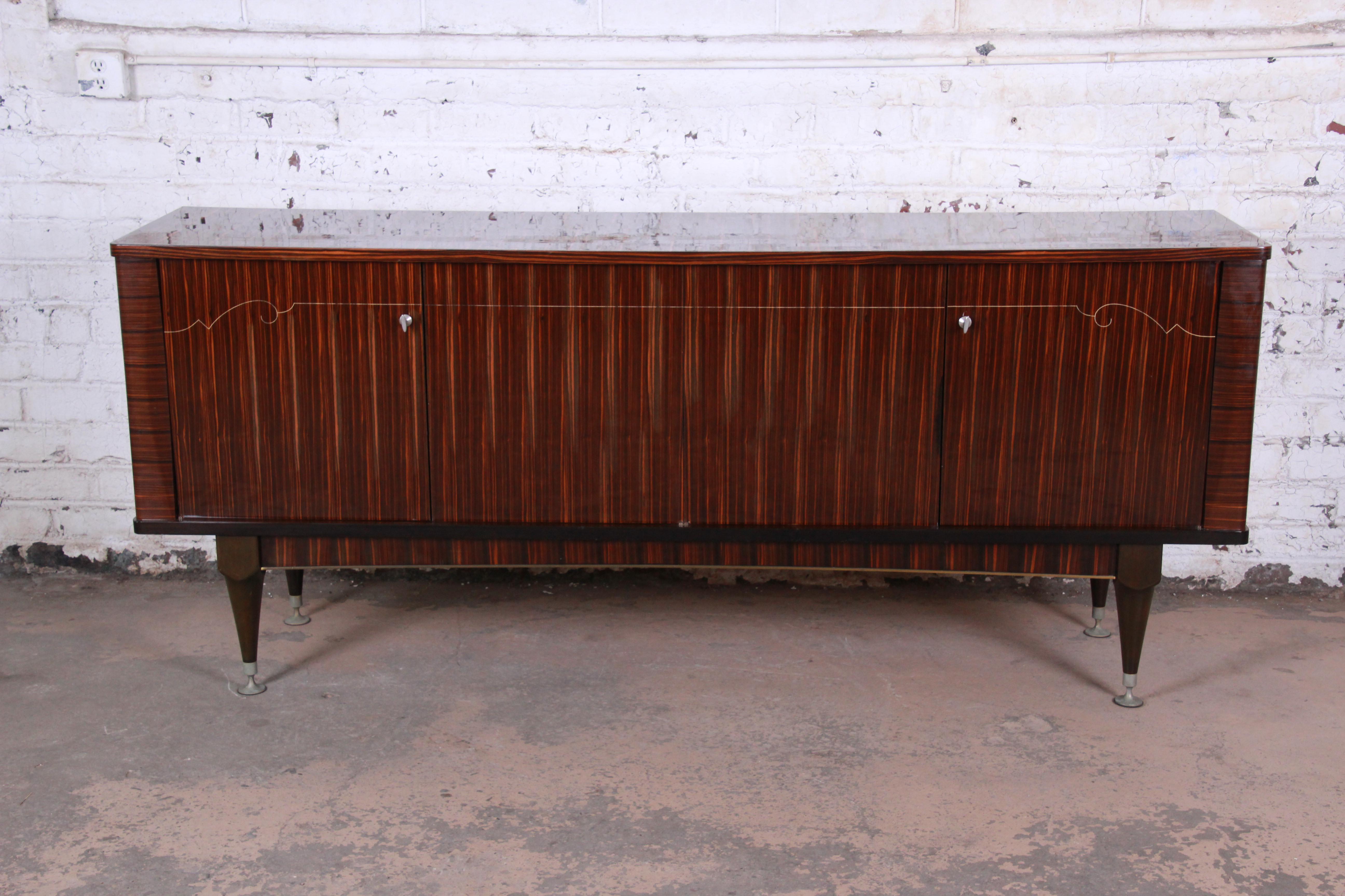 Ein herausragendes französisches Art-Déco-Sideboard, eine Kredenz oder ein Barschrank von N.F. Ameublement. Das Sideboard besticht durch die Maserung von Makassar-Ebenholz mit einer dünnen, dekorativen Perlmuttintarsie. Er bietet reichlich Stauraum