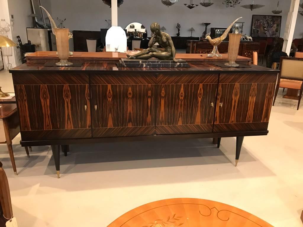 Stunning French Art Deco exotic Macassar ebony buffet or credenza, circa 1940s. Having incredible bookmatched wood, with Interior finished in lemonwood. The brass hardware accents the buffet beautifully. The legs are ebony with brass feet giving it