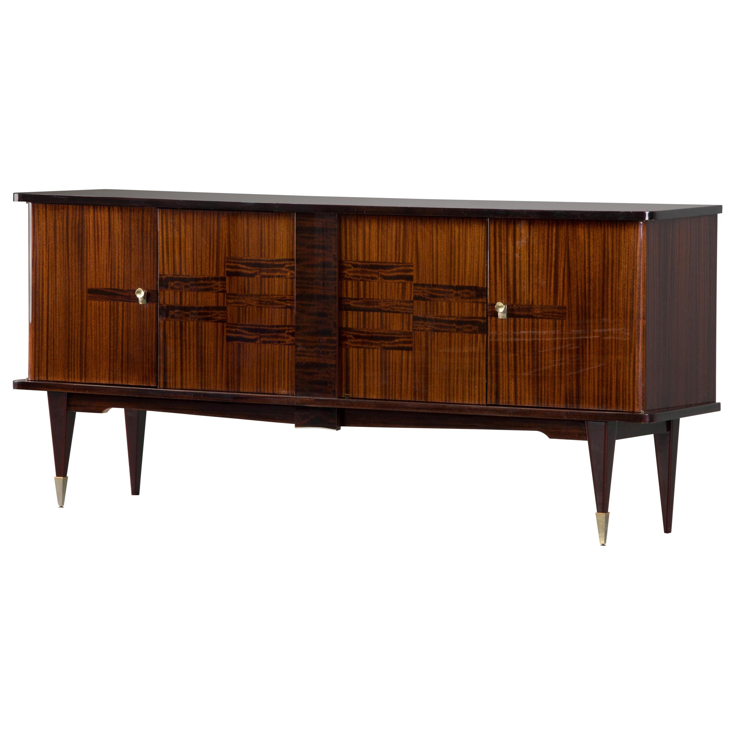 French Art Deco sideboard, credenza, with bar cabinet. The sideboard features stunning Macassar ebony wood grain with a decorative pattern design. It offers ample storage, with shelve behind two doors on the left and three drawers under and