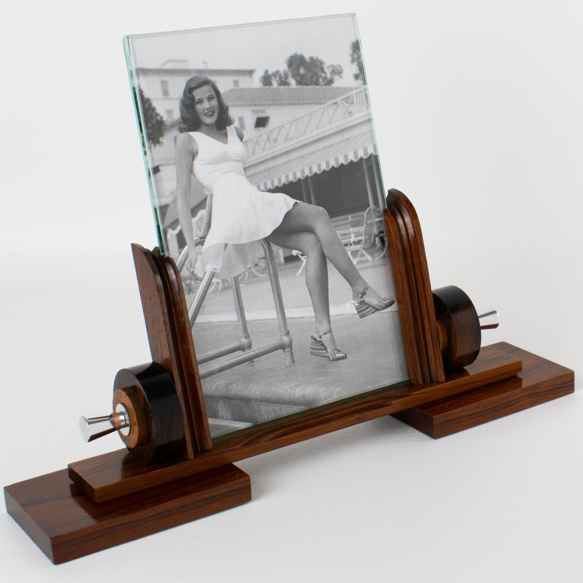 This stunning Art Deco modernist picture frame features a thick, hand-rubbed Macassar wood plinth complemented by carved Macassar wood holders and ornaments, all set off with ornate chrome accents. The photo frame is complete with two glass sheets