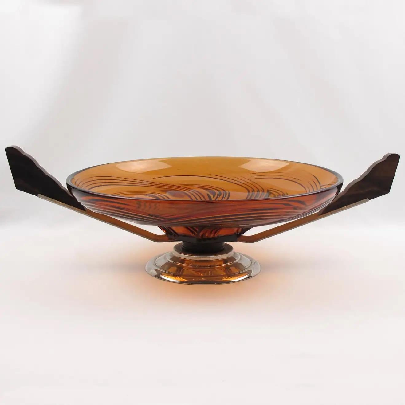 This stylish French Art Deco modernist centerpiece or bowl features a large round molded glass bowl with a swirled pattern in a lovely transparent burnt orange tone. The pedestal base is in chromed metal and Macassar wood. The centerpiece is adorned