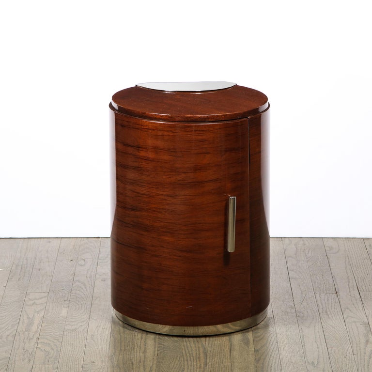 This elegant Art Deco Machine Age nightstand/ end table was realized in France, circa 1935. It features a cylindrical body with a streamlined front that opens via a cylindrical lustrous chrome streamlined handle to reveal an inner compartment with a
