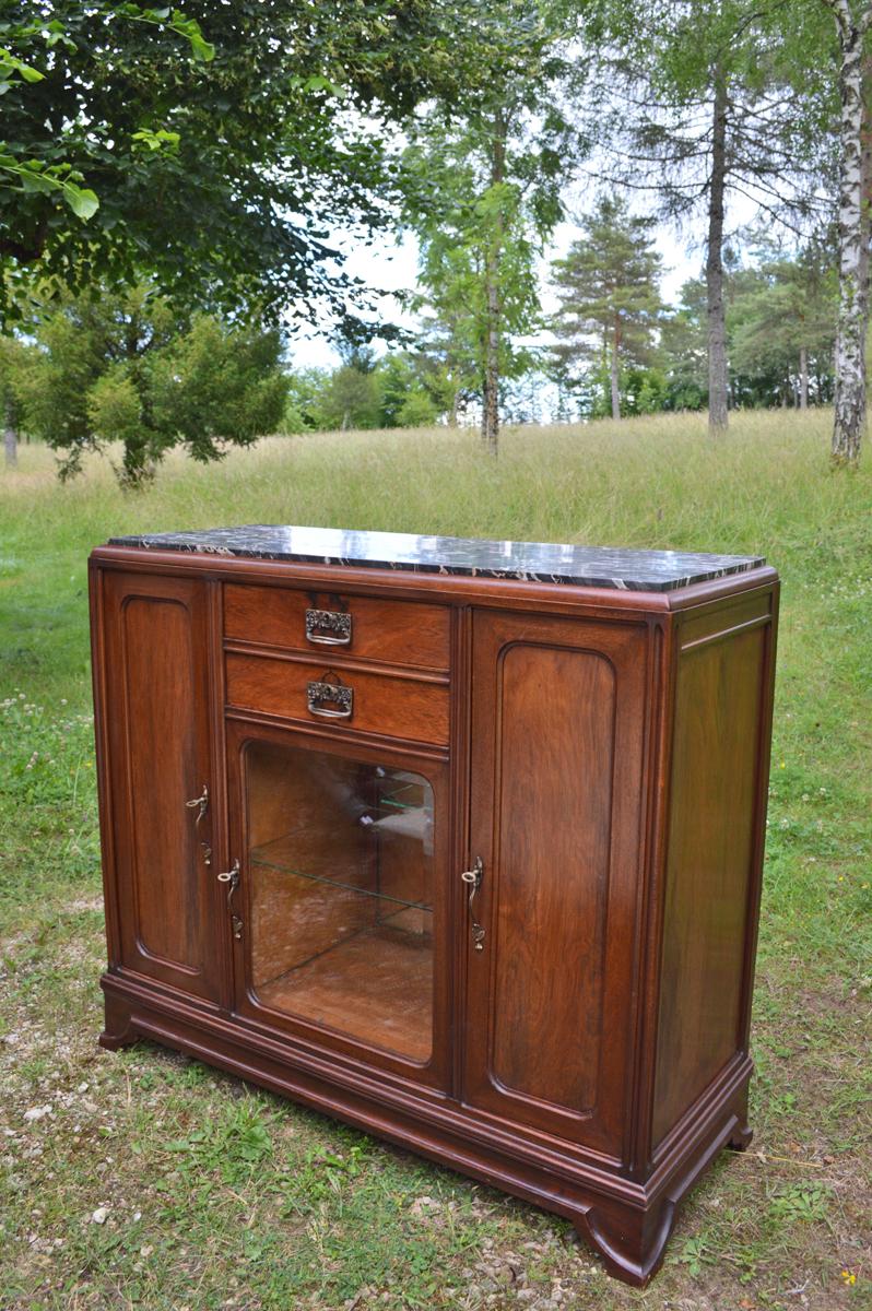 This buffet originates from the transition period between Art Nouveau and Art Deco and was produced, circa 1920.

The piece is made in mahogany with brass fittings and a veined marble top.

The piece comprises two drawers, one showcase with a