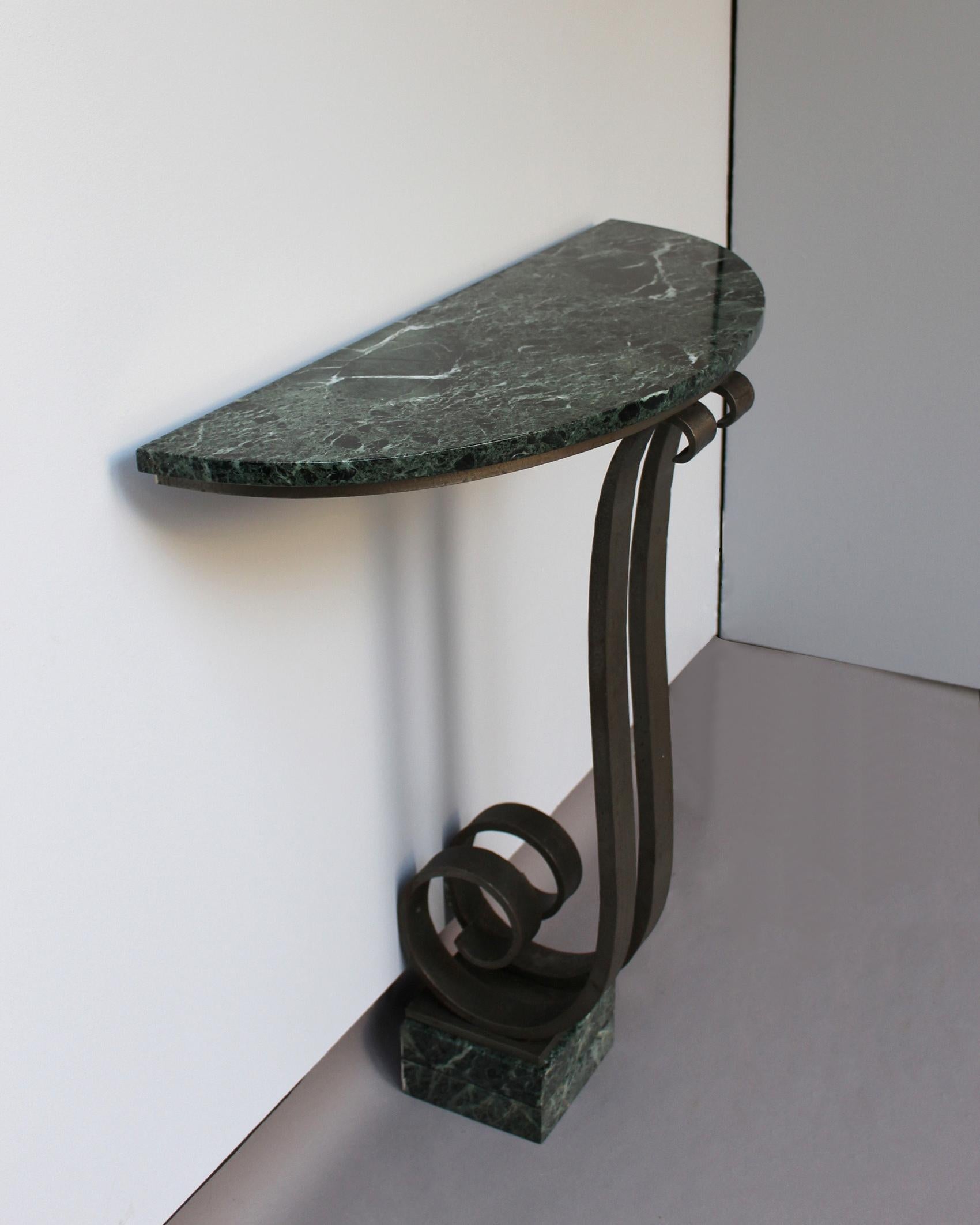 A French Art Deco console with a hammered wrought iron pedestal that supports a green marble top.




       