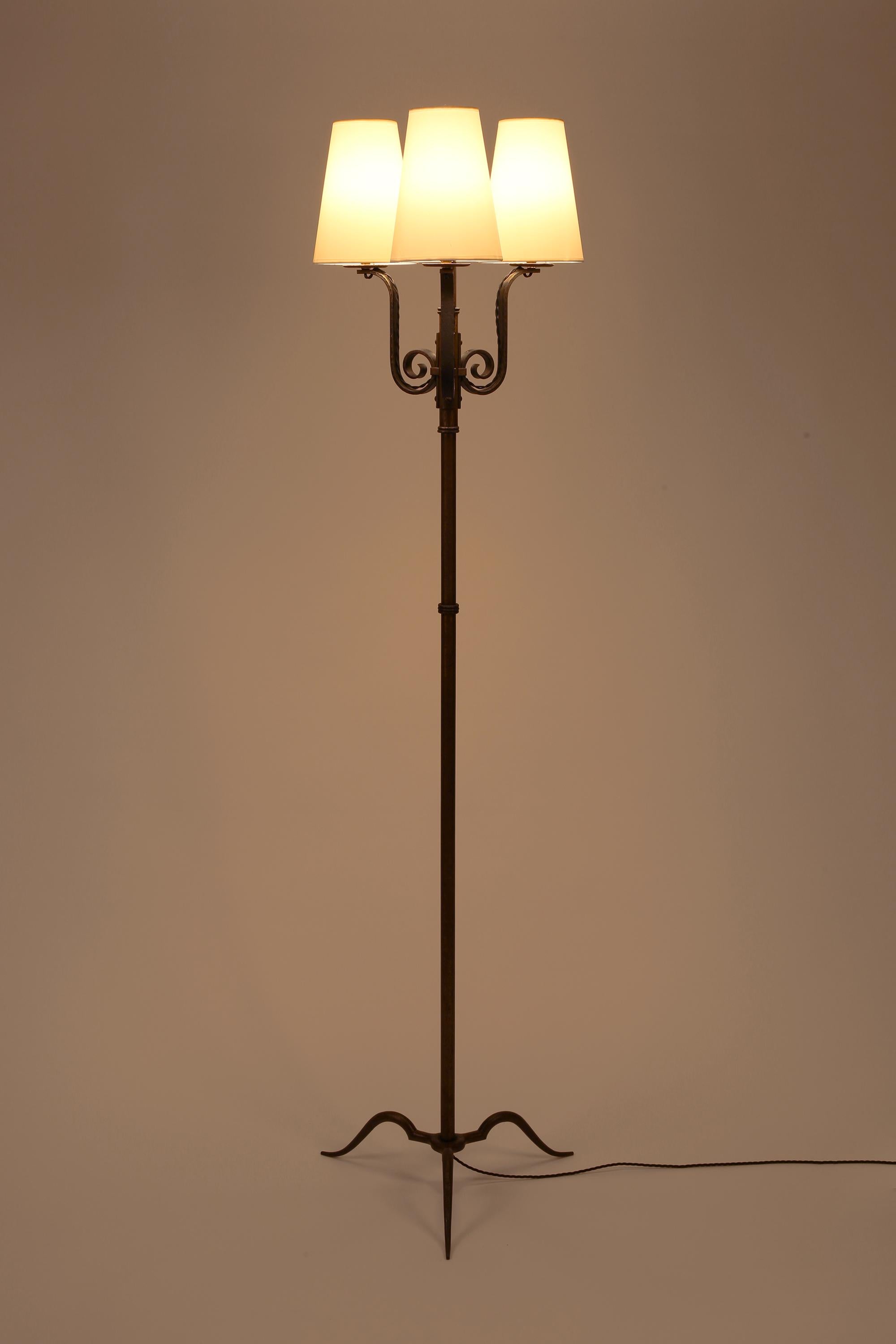 Eine schicke Stehlampe aus geschmiedetem Eisen im Art-Déco-Stil von Michel Zadounaïsky (1903-1983). Drei maßgeschneiderte Kegelschirme aus weißer Seide sitzen auf geschwungenen Armen über einem einfachen, geknickten Stiel mit formschönem Dreibeinfuß
