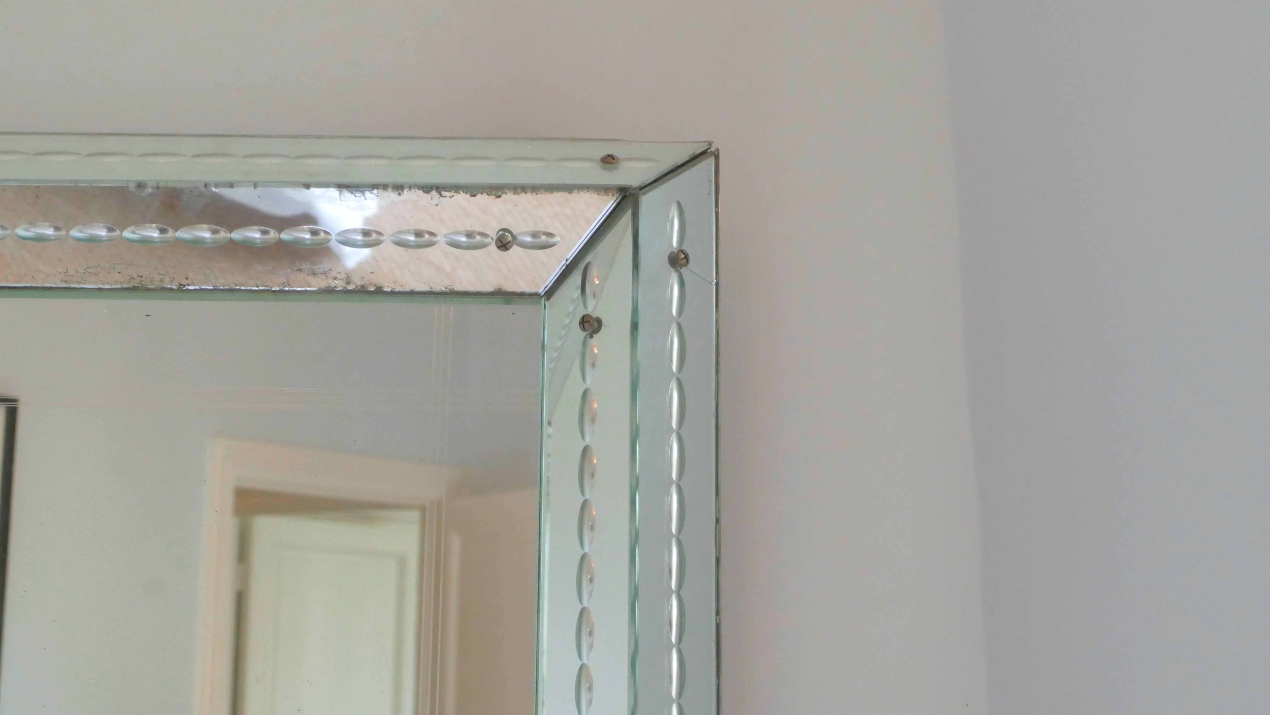 This weighty mirror from the 1940s has aged gracefully; its charming patina now imbues it with a lovely romantic feel. Displaying elements of the late Art Deco period and early modernism, the mirror was modelled after the style of French designer