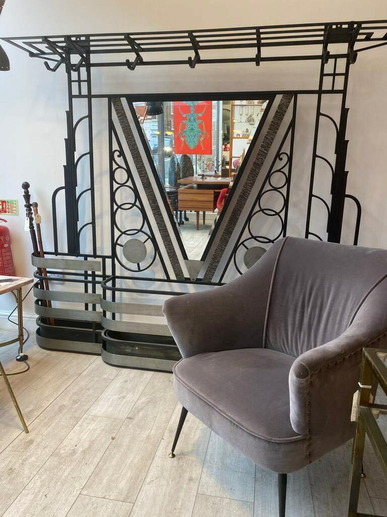 A stunning and rare French Art Deco metal mirrored hall stand.
Beautiful piece surmounted by a luggage rack and with coat hooks, centred by a triangular beveled glass mirror plate flanked by rows of concentric circles, the break-front shaped base