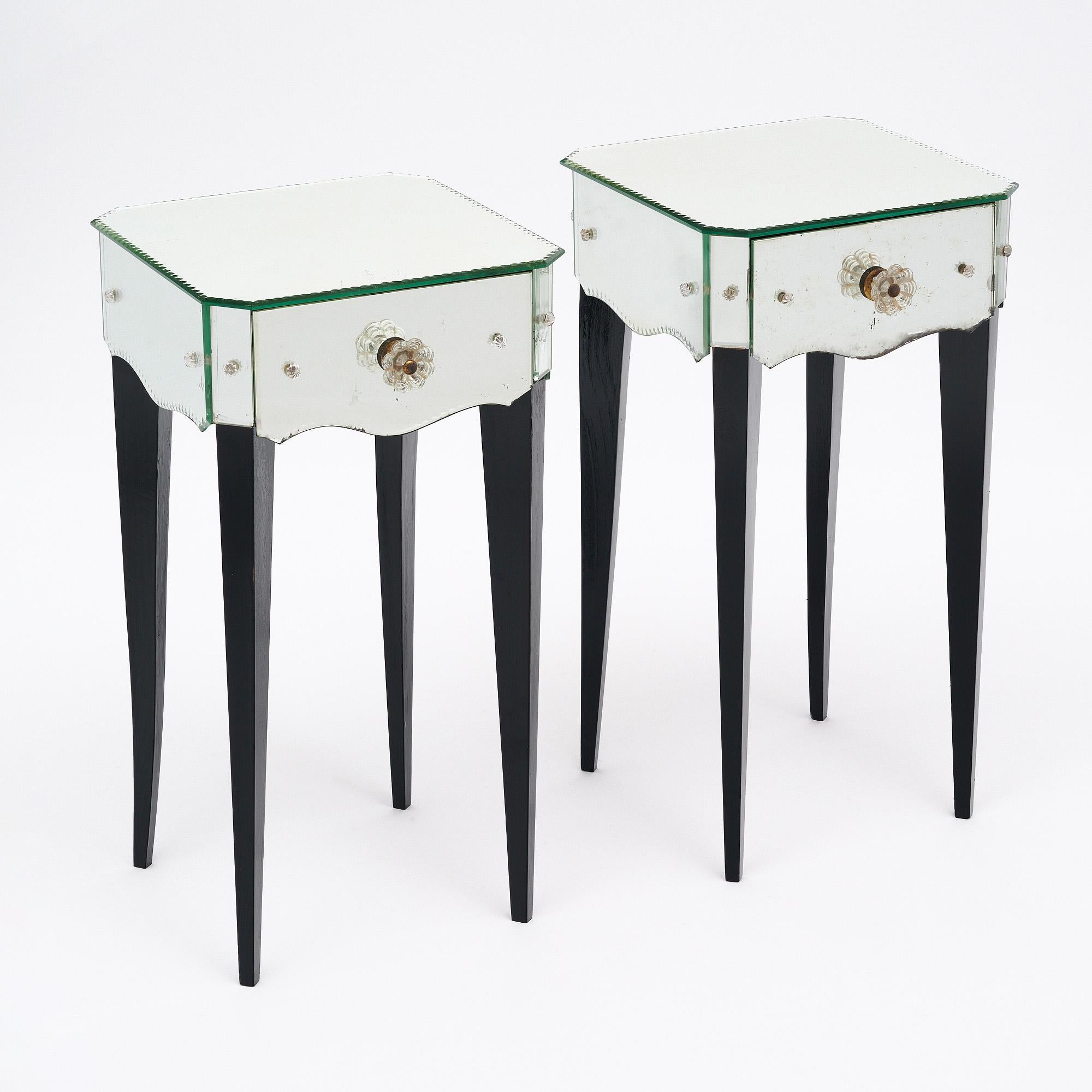 Pair of side tables from France. This Art Deco period pair have classic deco proportions and long tapered, ebonized legs. Each is veneered with original mirror, held in place with decorative glass finials. The mirror features a scalloped edge as