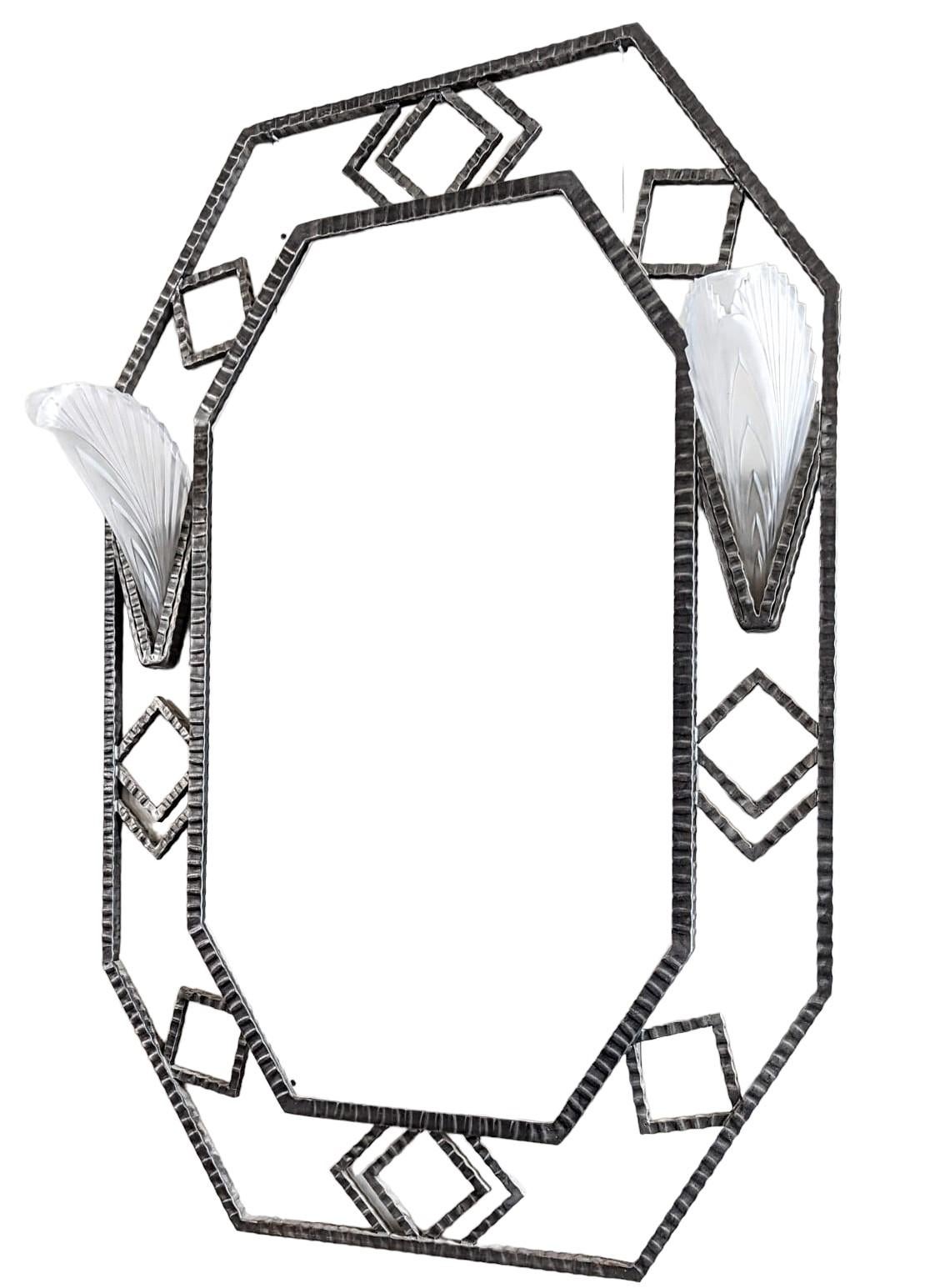Ein atemberaubender französischer Art Deco Modern Schmiedeeisen-Spiegel mit geometrischen Motiven mit einem Paar Vintage klaren Milchglasschirmen in einem Federmuster. Jeder Schirm ist für eine Kandelaberlampe (max. 65 Watt) geeignet. Der Rahmen