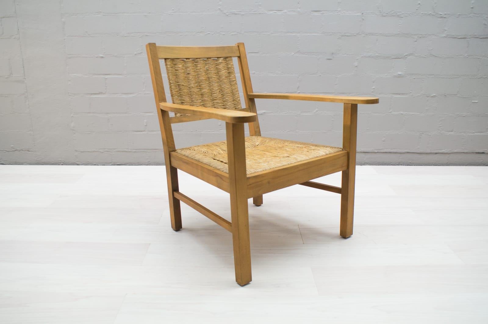 An exemplary example of Art Deco Modernist armchairs in the style of the French designer Francis Jourdain. The simple, straightforward composition is comprised of a stained beech frame with a slanted back and wicker upholstery as well. The wood