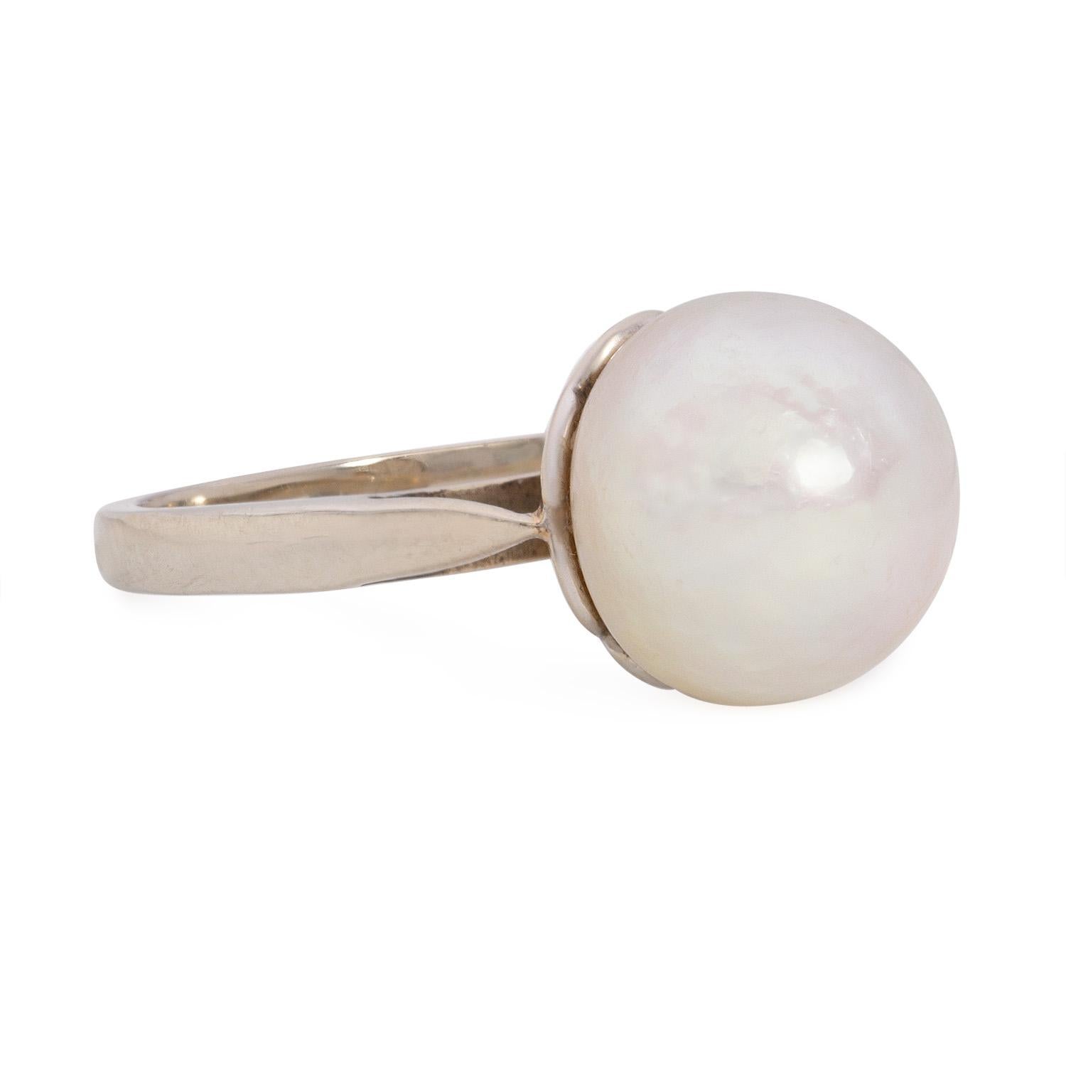 Dieser exquisite Art-Déco-Ring aus den 1920er Jahren ist ein wahres Zeugnis der Eleganz und Raffinesse seiner Zeit. Der aus glänzendem Platin gefertigte Anhänger ist mit einer seltenen und faszinierenden Perle bestückt: einer 9,8 mm großen, runden