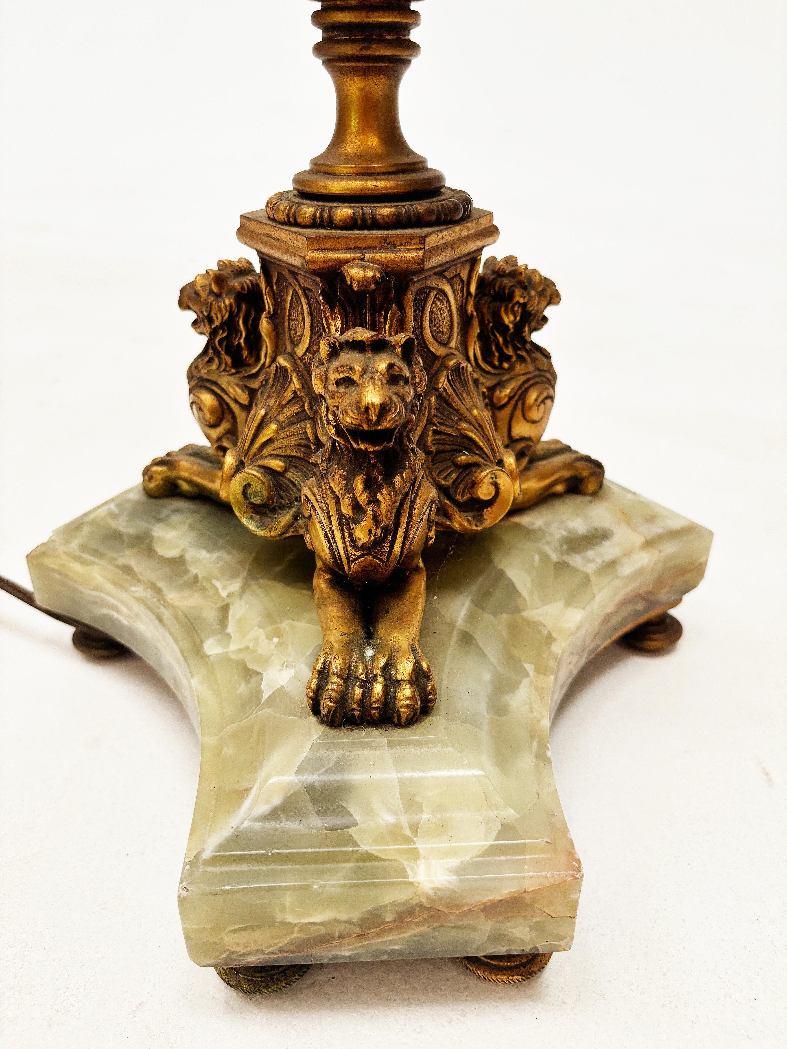 Questa lampada da terra francese Art Deco Neoclassica assolutamente mozzafiato è a dir poco una magnifica opera d'arte. Costruita in metallo fuso in bronzo, la base della lampada vanta leoni appollaiati su una bellissima onice verde con venature di