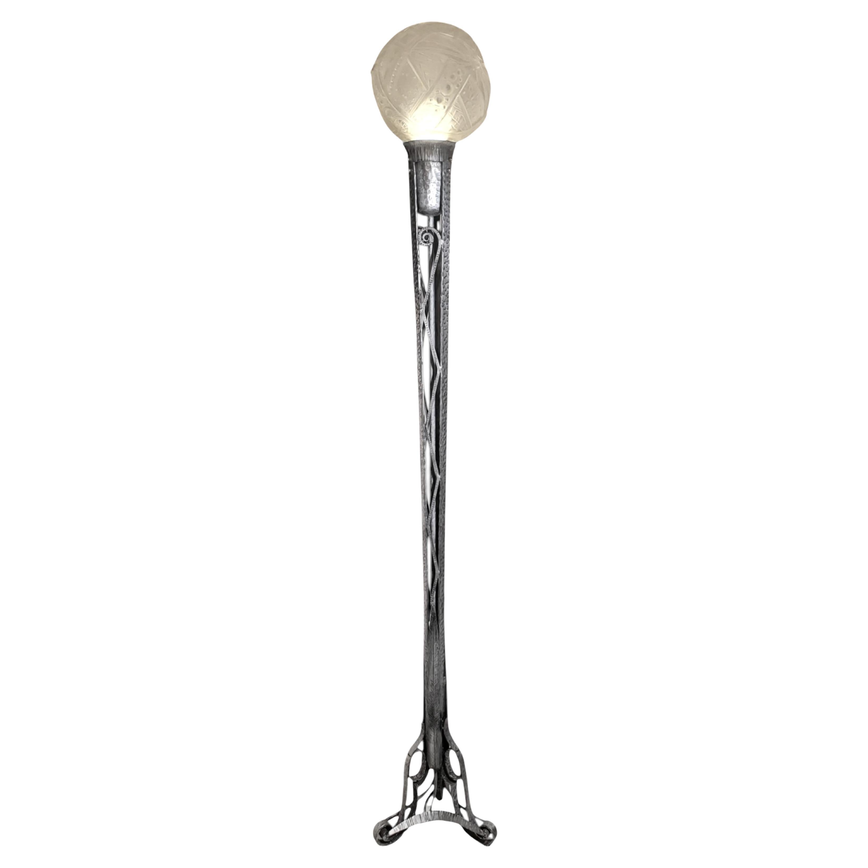 Torchère Art déco française vers 1930, en fer martelé à finition nickelée. 
La lampe sur pied comporte un grand globe moulé en verre d'art dépoli, signé par le célèbre verrier Muller Frères de Luneville, en France. Ce globe particulier, connu sous