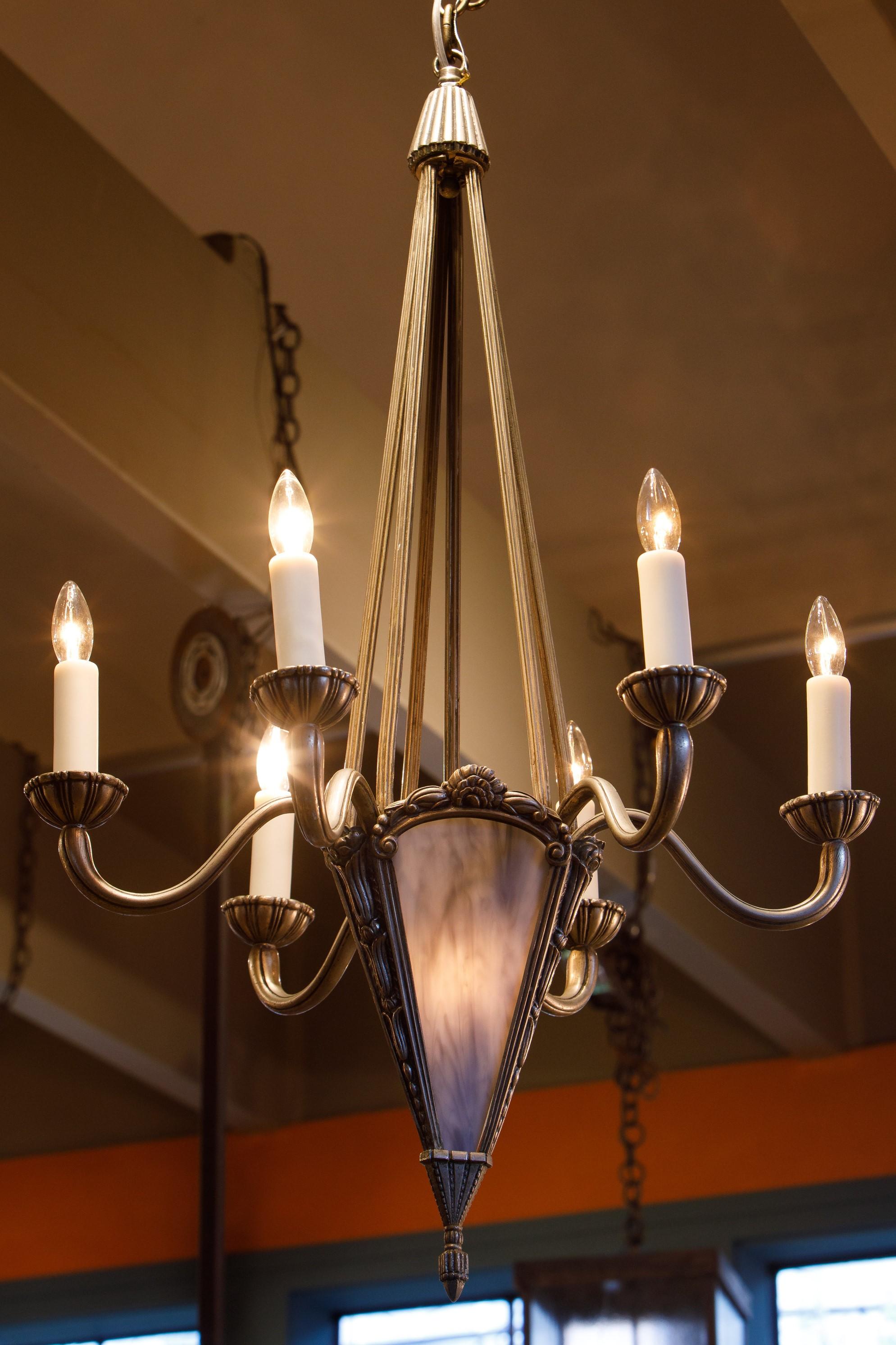 This is an impressive well preserved example of Art Deco lighting. Nickle on bronze chandelier circa 1940s with newly cut art glass panels. The light is re-wired for the USA with candelabra/ E12 sockets and one candelabra socket in the interior of