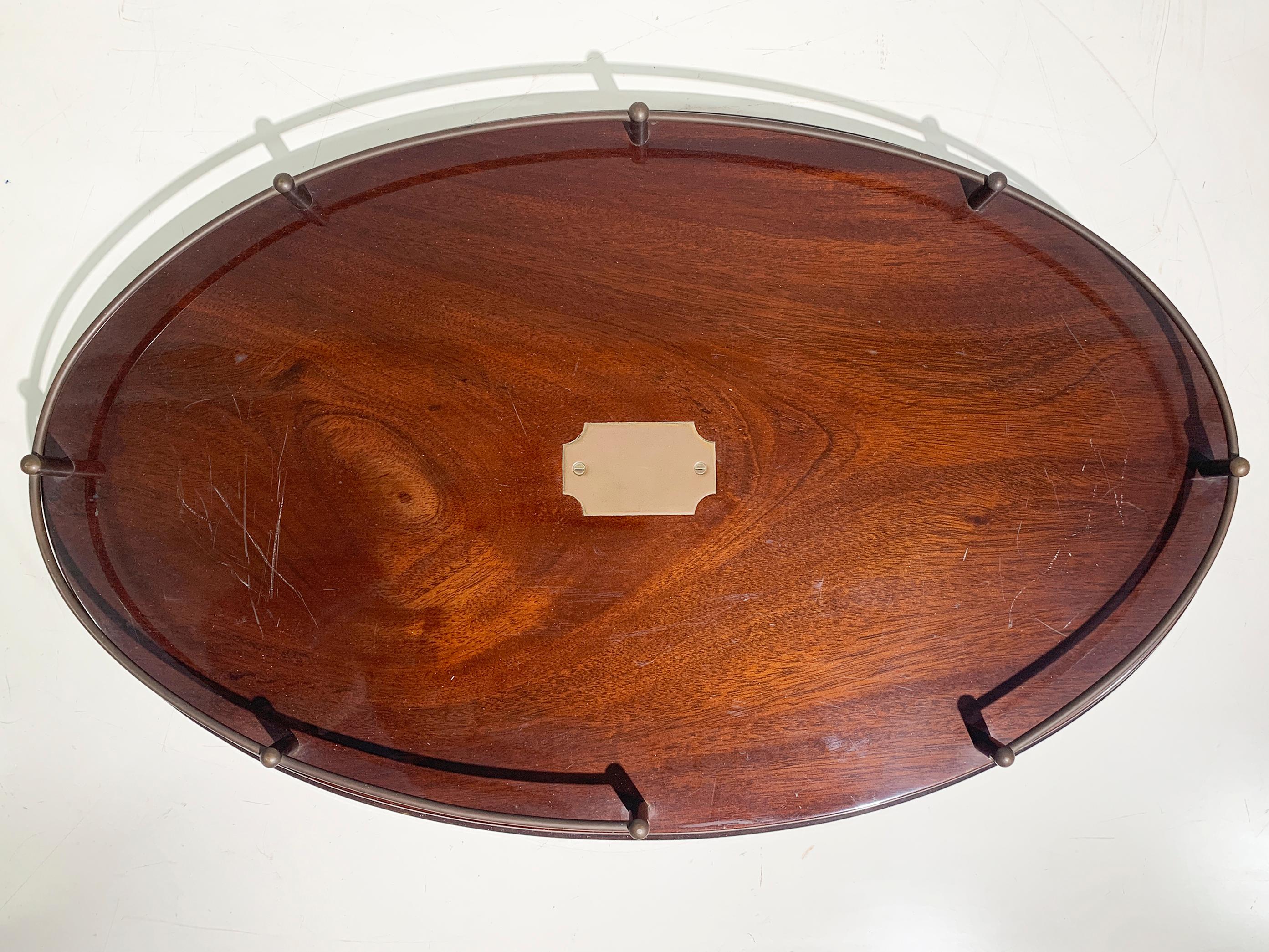 A refined French Art Deco oval gallery tray from circa 1930, crafted from beautifully polished noble wood with a warm, rich grain, and framed by an elegant brass gallery rail. The design reflects the sleek sophistication of the Art Deco era, with