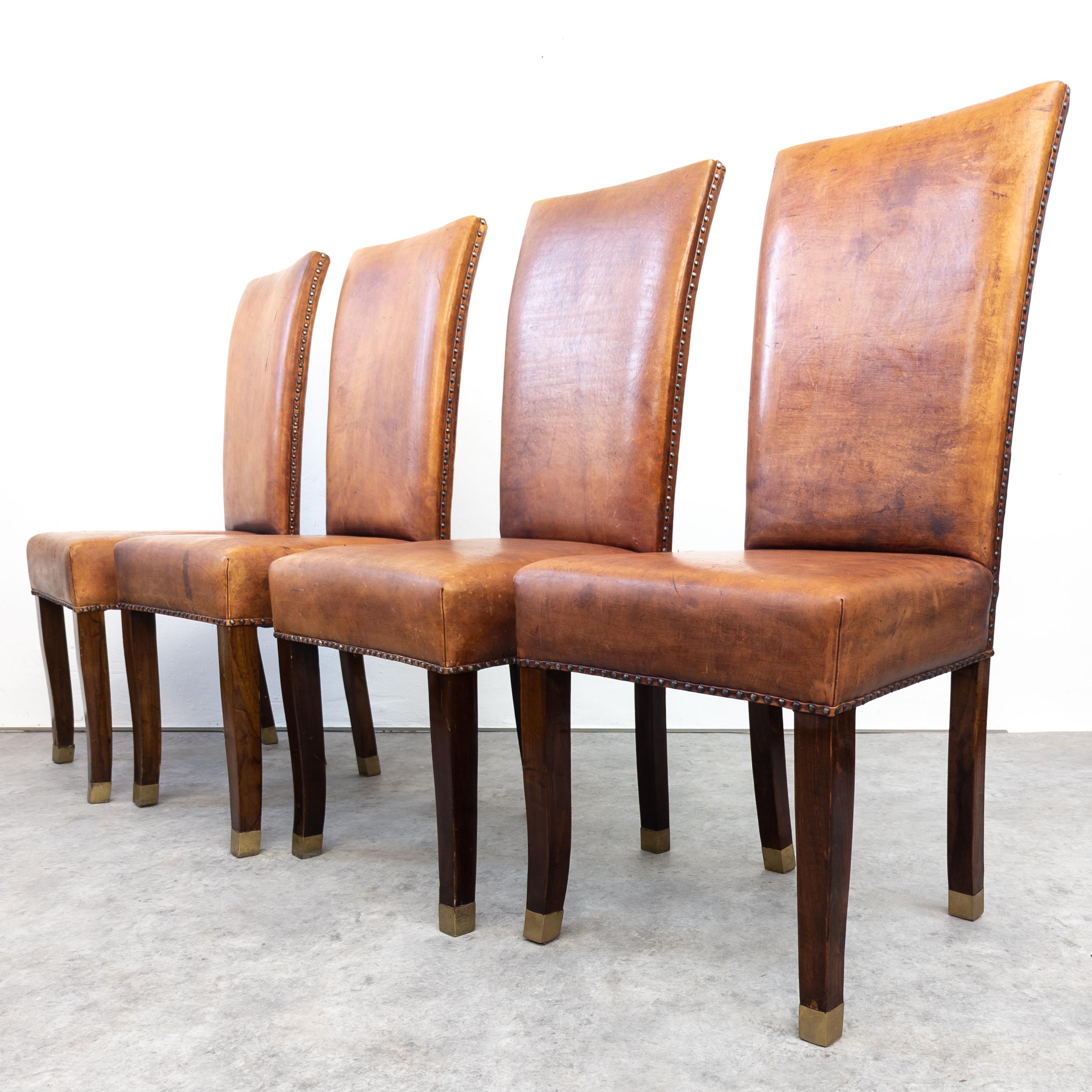 Stunning French Art Deco dining chairs. Made of solid oak and thick saddle leather, with brass fittings. Chairs are firm and steady. Strong patina on the leather with some scratches. In overall good vintage condition. Wear consistent with age and