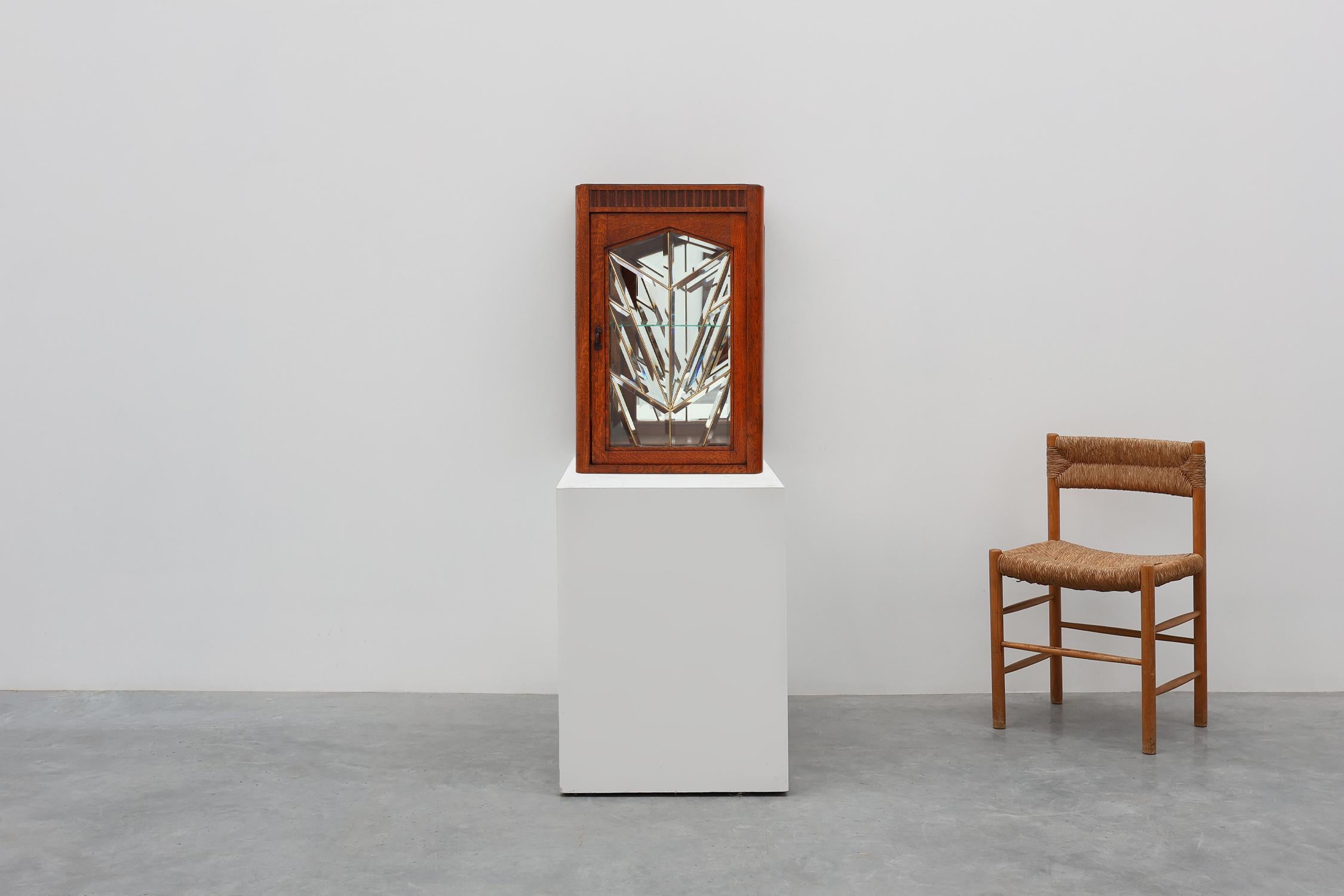 France / 1920 / cabinet / wood, glass, mirror, metal / Art Deco

An elegant French Art Deco cabinet from around 1920, crafted from warm oak and featuring a striking geometric beveled leaded-glass door.
u2028A finely carved decorative frieze adorns