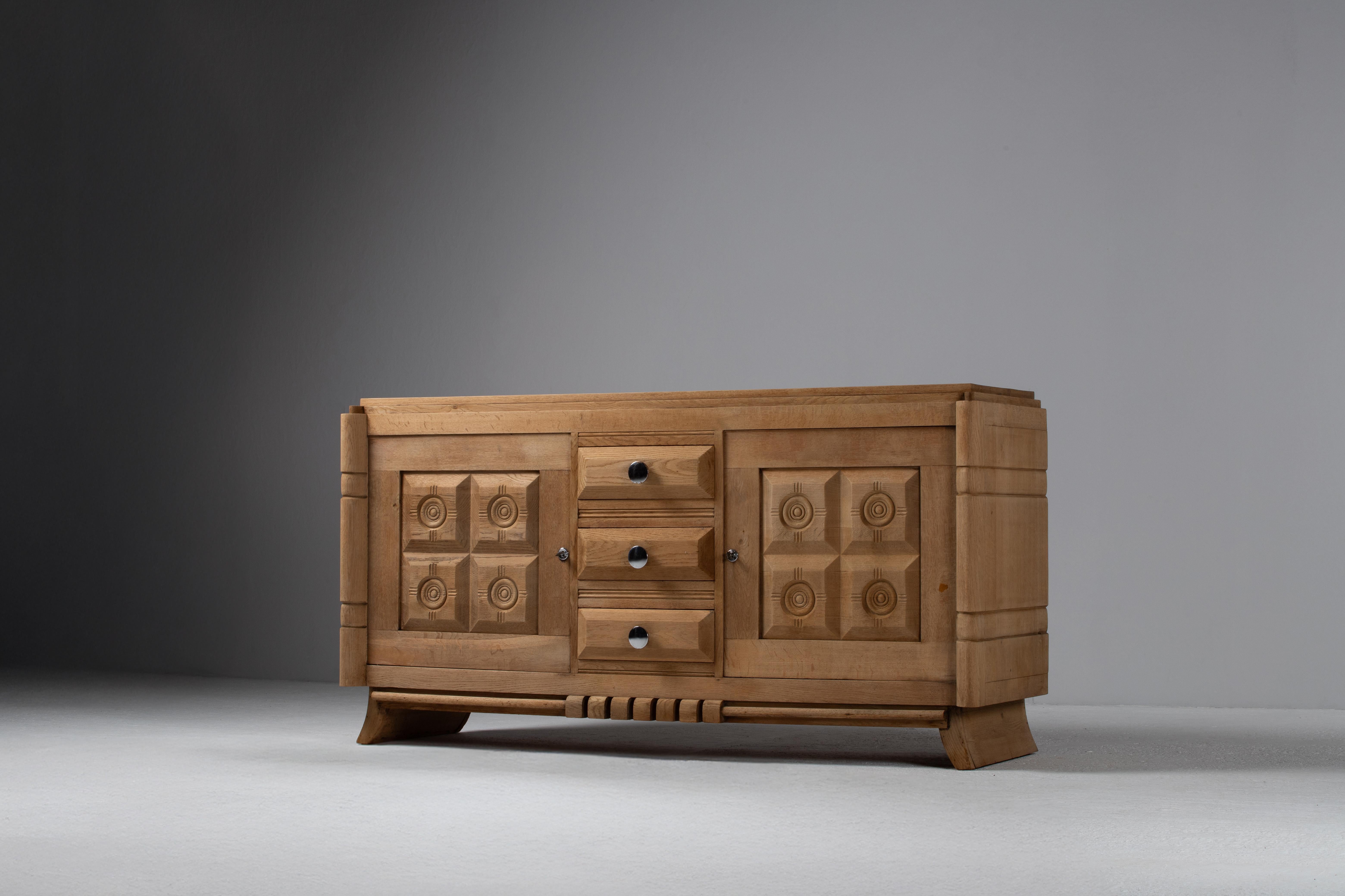 Ce buffet Art déco français des années 1940 est un exemple frappant de travail du bois sculptural et de composition géométrique audacieuse. Fabriqué en chêne massif, son design est défini par des panneaux en relief tissés complexes sur les portes,