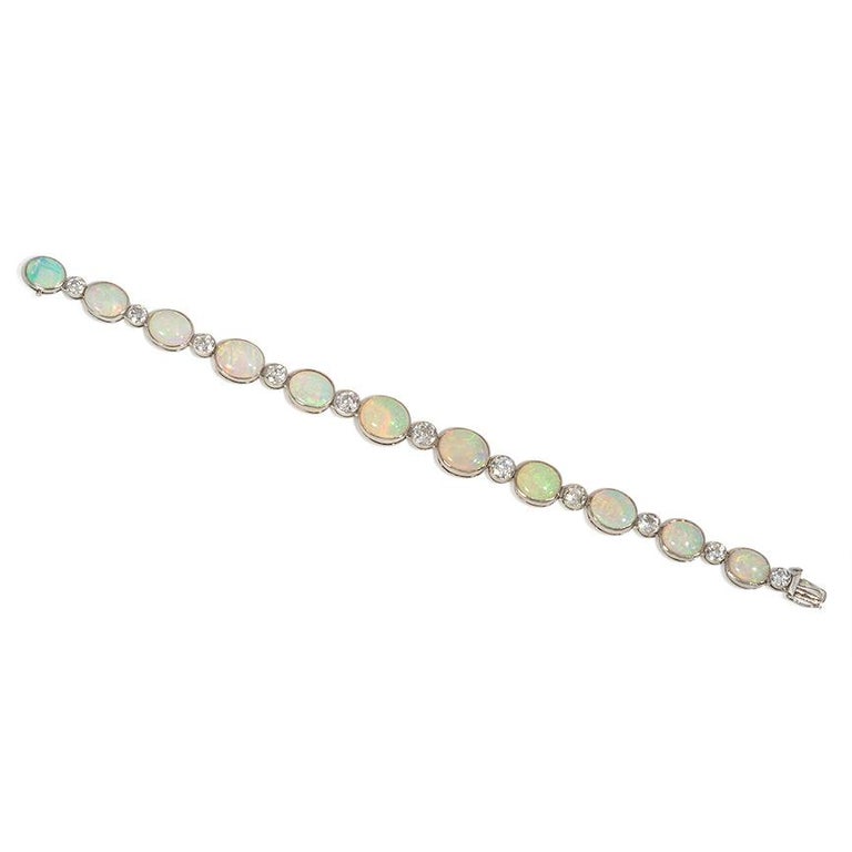 An Art Deco collet-set diamond and opal line bracelet of tapering design, in platinum.  France.  Atw. 3.80 ct. diamonds.