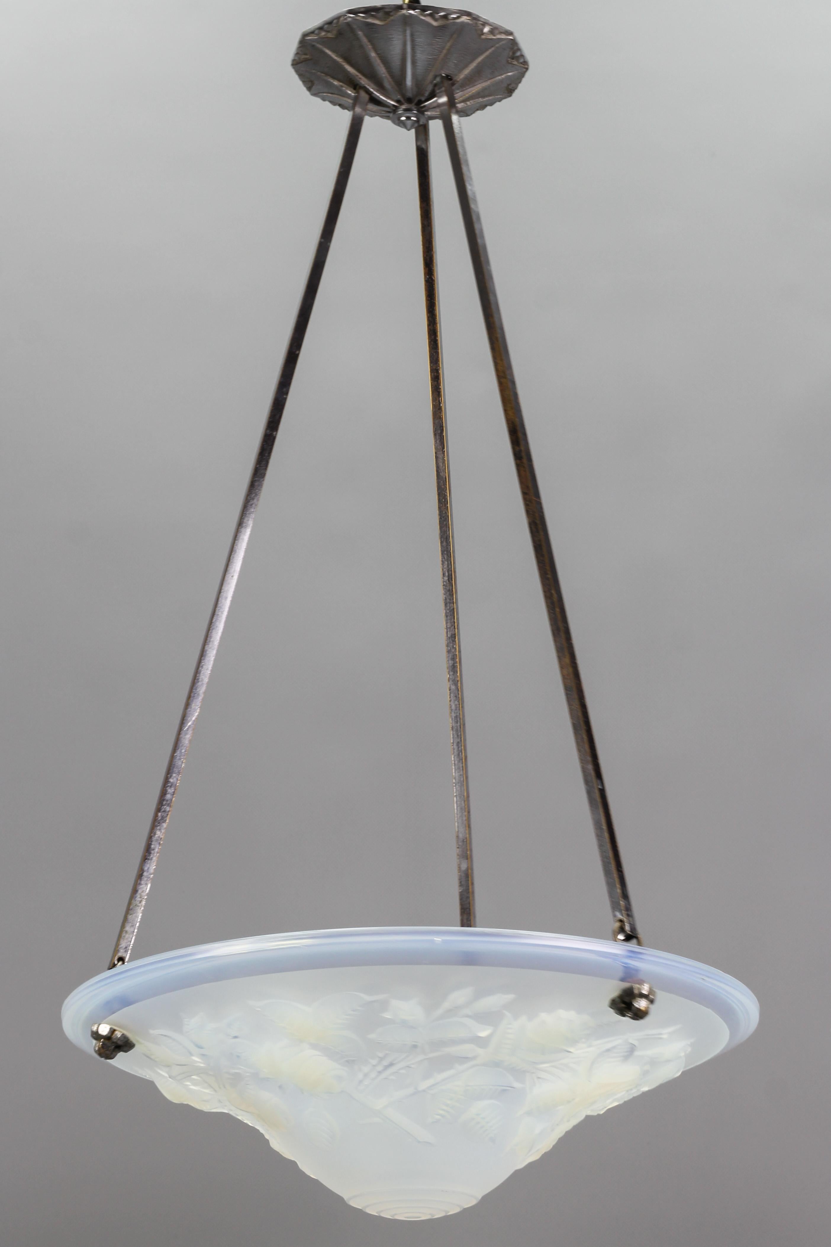 A beautiful French Art Deco pendant light made of adorable opalescent glass with a floral design – intricately detailed roses, leaves, and rosebuds. The opalescent glass bowl is signed ” P. Maynadier France”, hung at a chromed brass and bronze