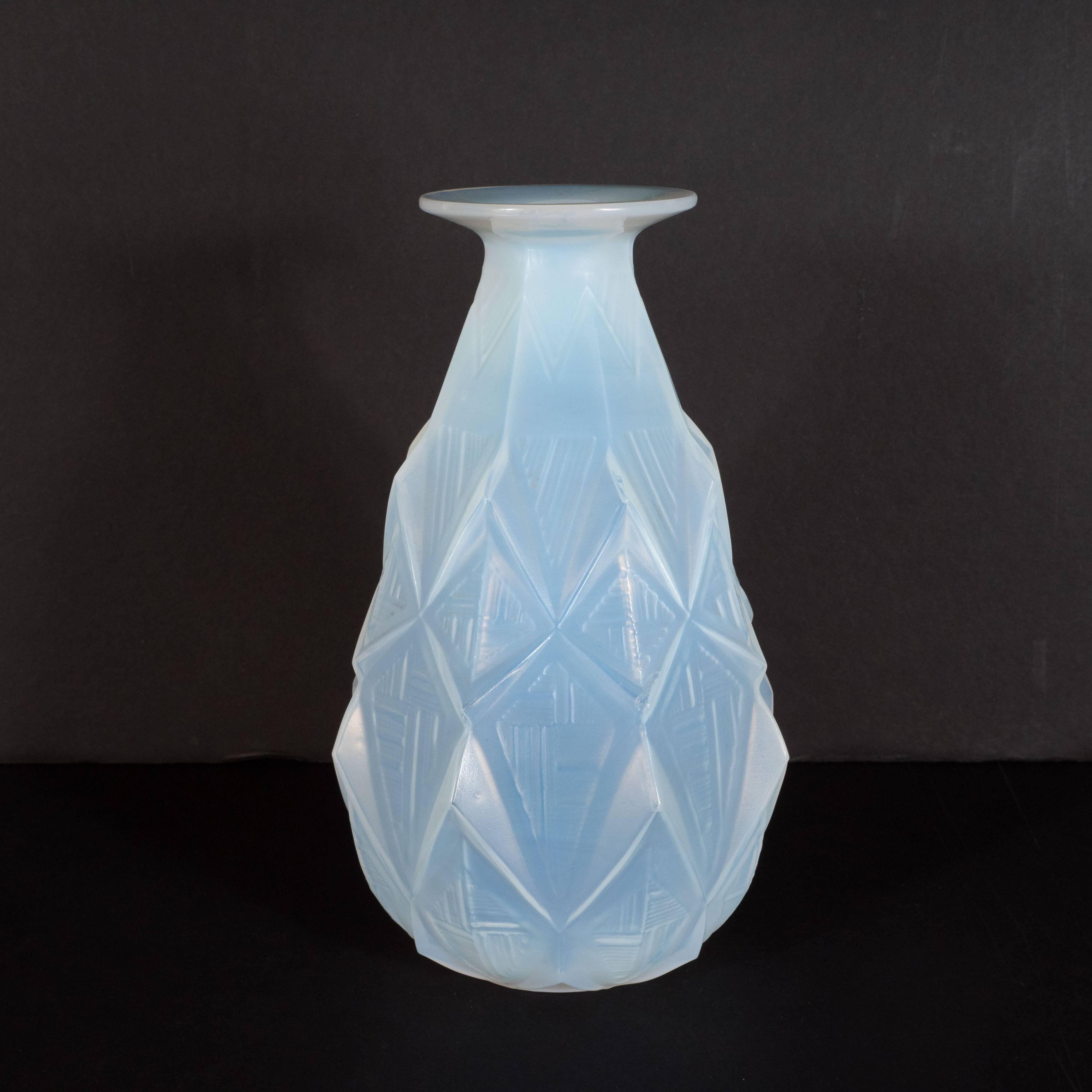 This stunning vase was realized by the illustrious glass blowing atelier, Sabino, in France circa 1930. It features a subtly tapering body that dramatically flares at its mouth, as well as raised rectilinear geometric designs throughout. This is a