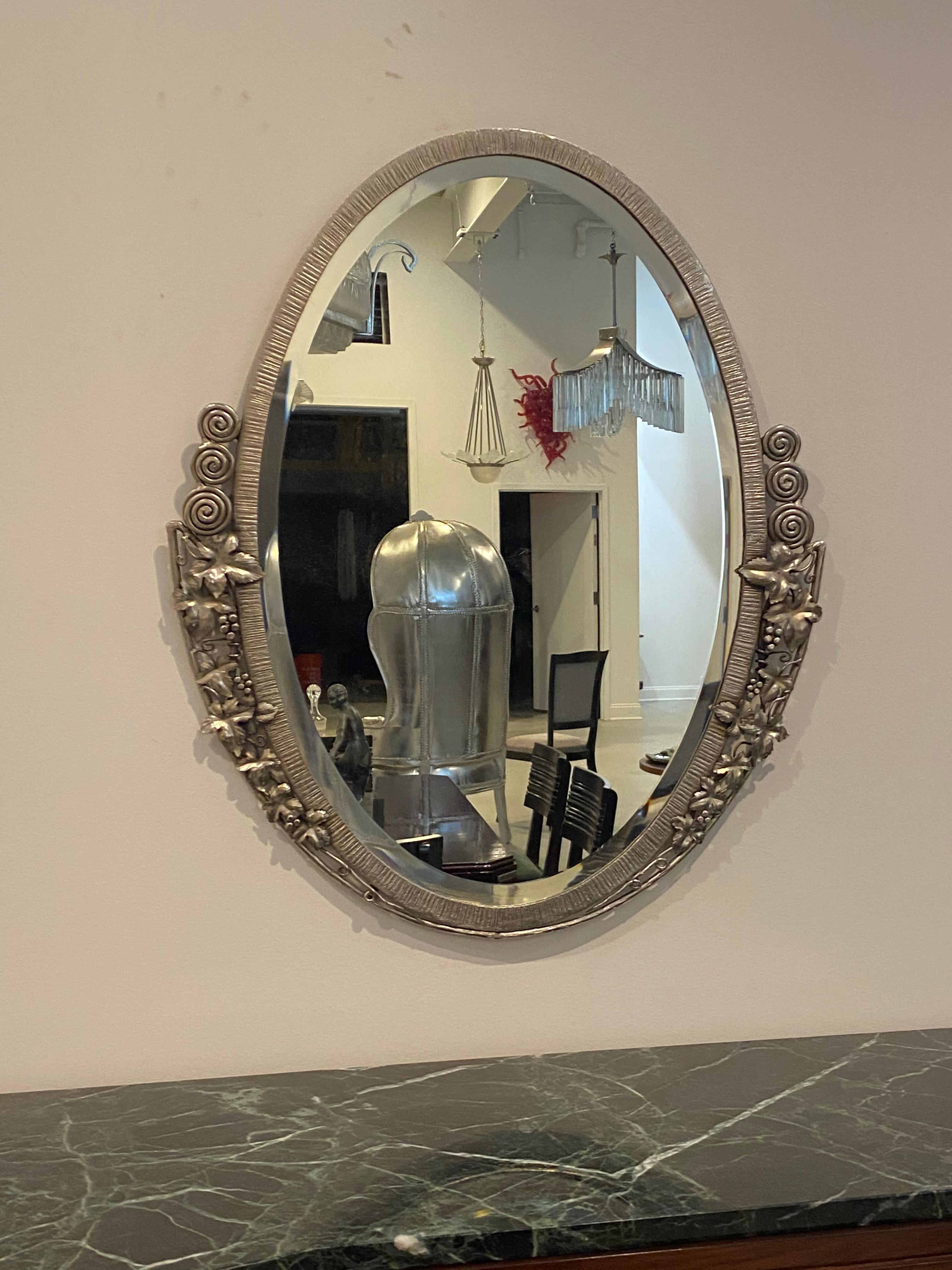 French Art Deco oval mirror with floral and geometric motifs. The frame has been re plated in a polished nickel. The mirror has been replaced with a new beveled mirror. 

  