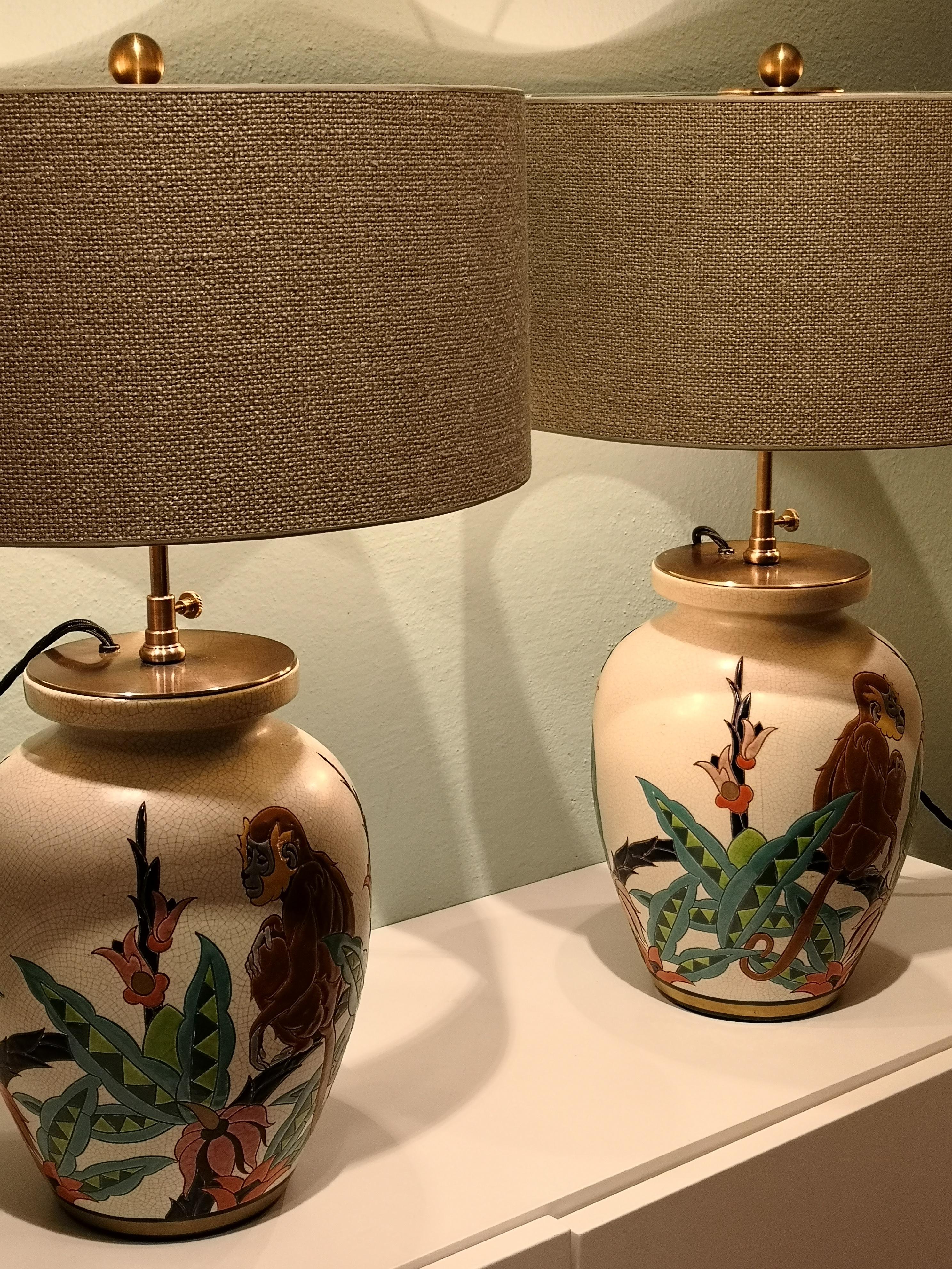 Pair of French Art Deco table lamps made from glazed ceramic vases. The vases are polychrome enamel on beige crazed background. Enamelled original stamp Orchies Moulin and numbered in the bottom. The decor shows monkeys and leafs with flowers in