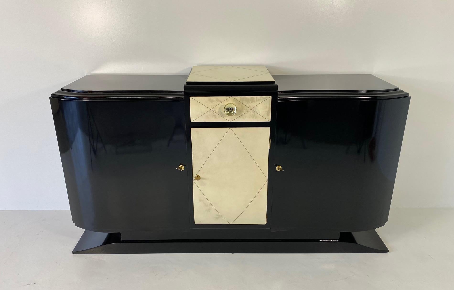 This Art Deco Sideboard was produced in France in the 1930s. 
It is completely black lacquered, the only exceptions are the central part of the top, the drawer and the central door, which are all covered in geometrical pieces of parchment. 
The
