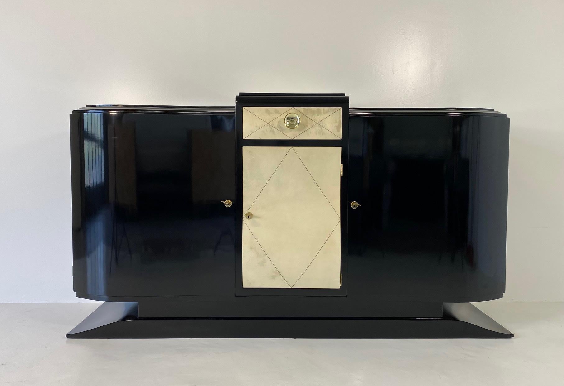This Art Deco sideboard was produced in France in the 1930s. 
It is completely black lacquered, the only exceptions are the central part of the top, the drawer and the central door, which are all covered in geometrical pieces of parchment. 
The