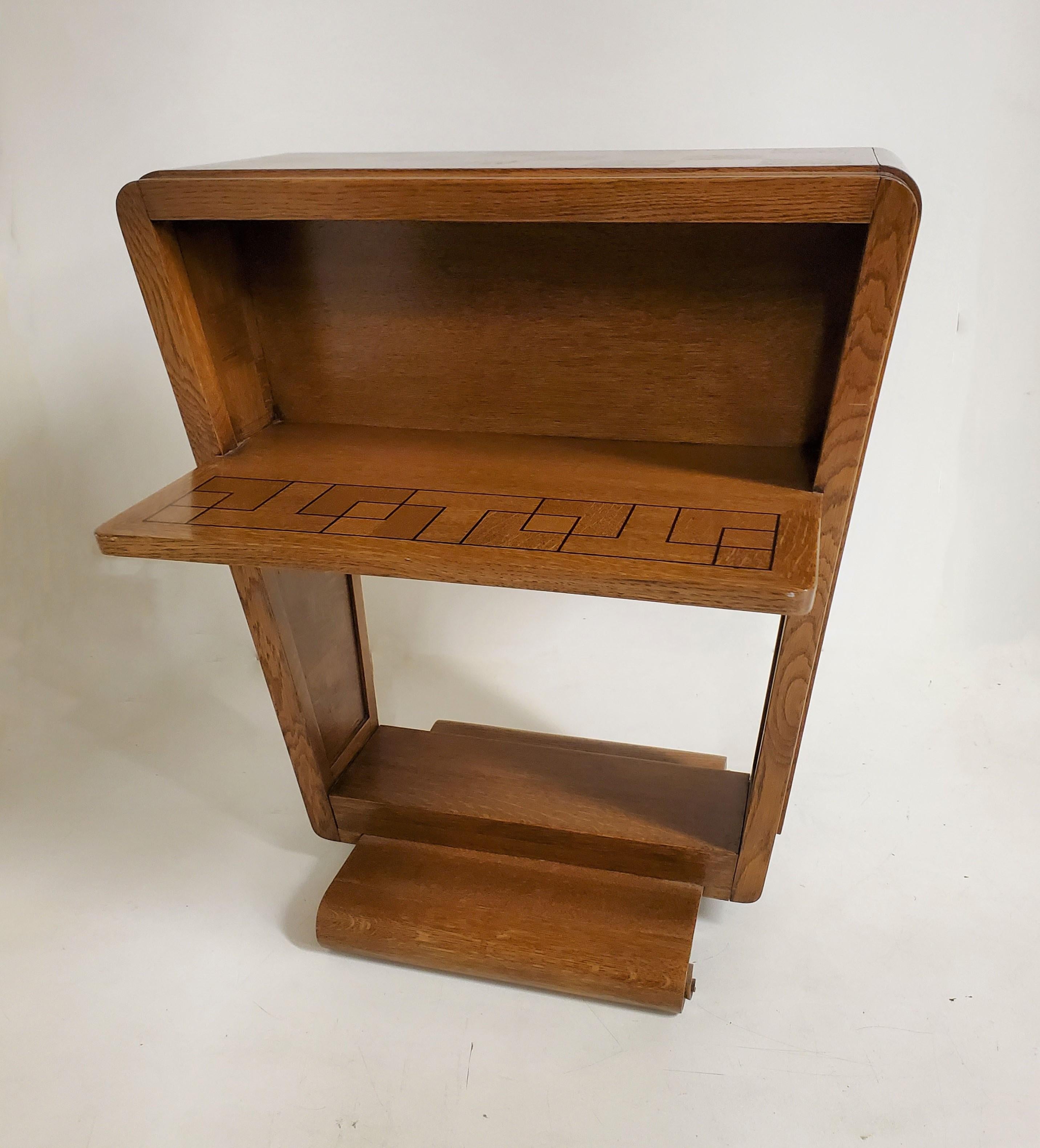 A rare and unusual Modernist side/ end table of cubist design with parquetry inlaid top, radius corners, angular side planks, and two fixed shelfs, the whole ending with a carved decorative scroll at each corner of the base. Attributed to André
