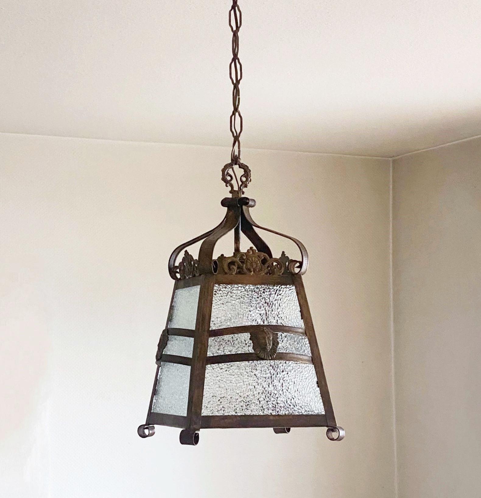 Arte Deco patinated iron and Glass four-sided Lantern decorate with a bronze face on each side, France, 1930s. A beautiful lantern for any space also suitable for covered outdoor areas. In very good vintage condion, great aged patina, glasses