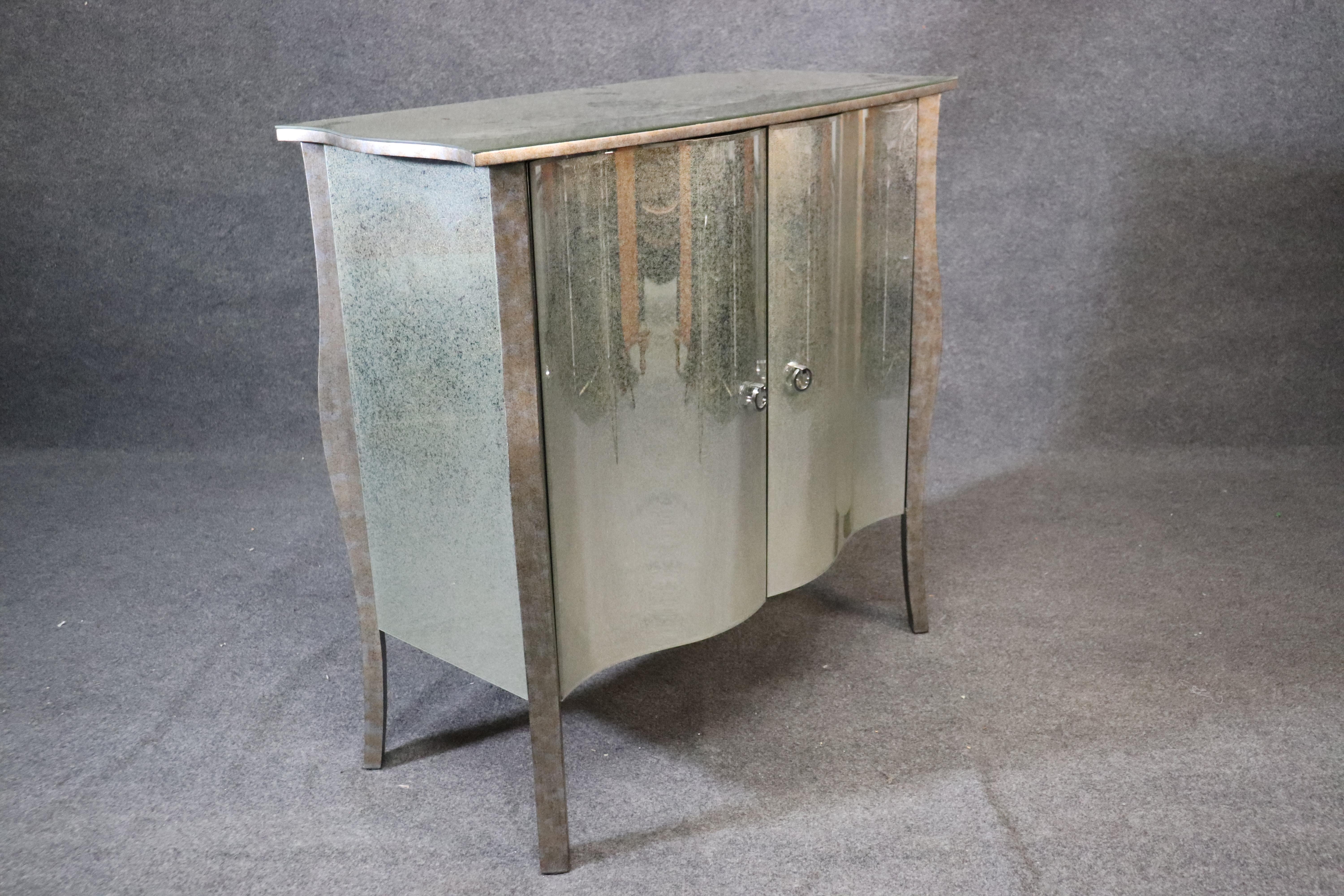 This is a gorgeous contemporary and nearly new patinate antiqued glass commode. The commode is done in the Art Deco style and is less than a year old. It has virtually no signs of wear and tear. The commode measures 38 inches tall x 40 wide x 18