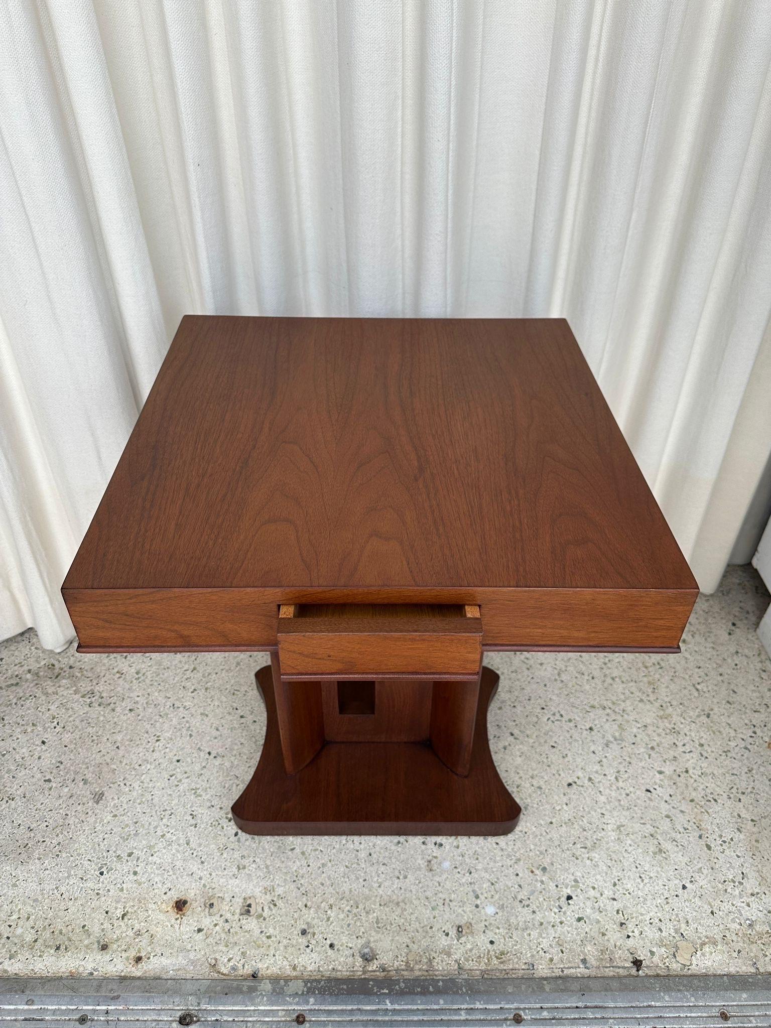 Maravillosa mesa auxiliar Art Decó con pedestal, recortes geométricos en la base y un largo cajón para guardar cosas.  El acabado de la madera es impecablemente limpio y es sencillamente una pieza impresionante.