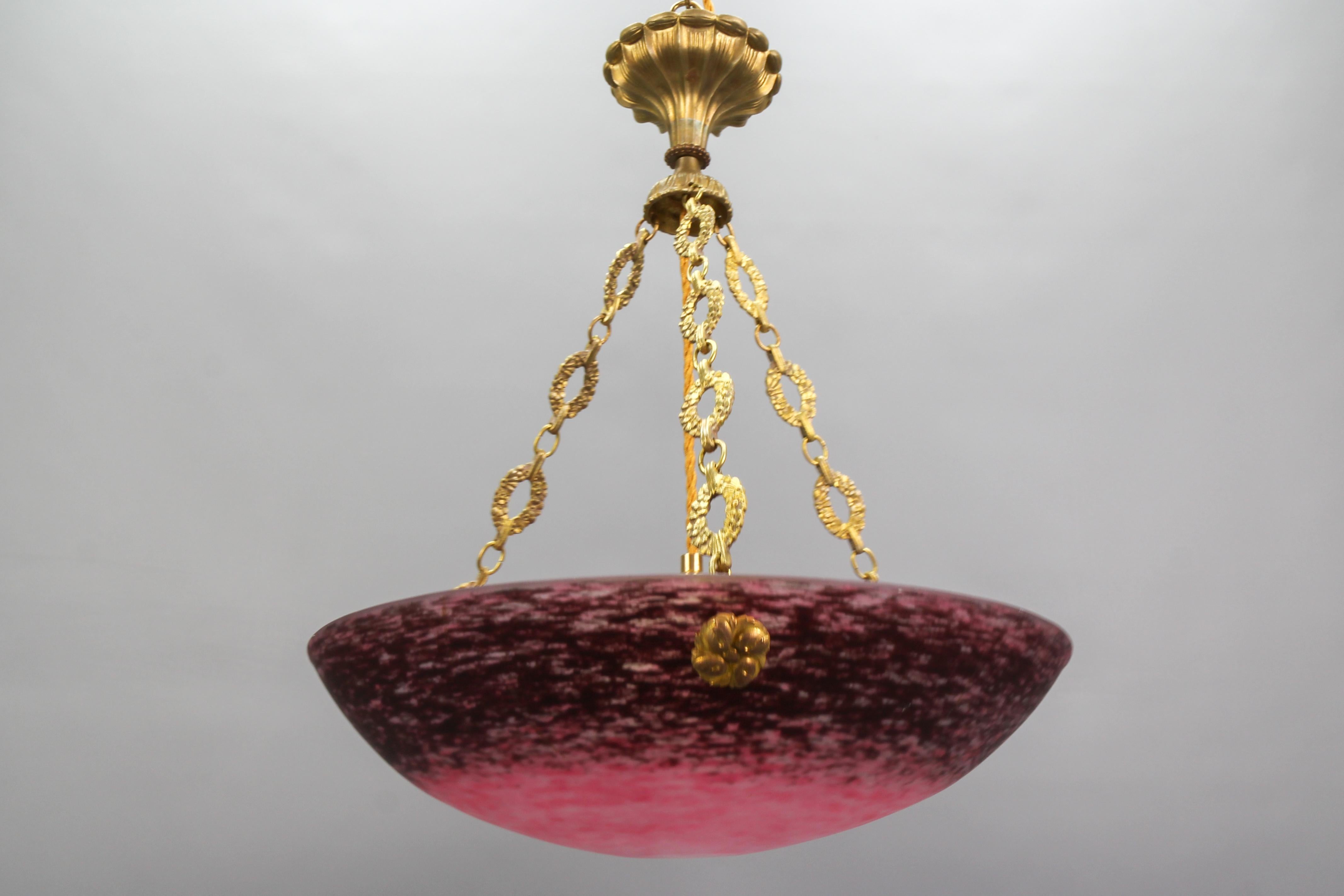 French Art Deco pendant chandelier by Charles Schneider from the 1920s.
This adorable French Art Deco period pendant chandelier features a large mottled “Pâte de Verre” art glass bowl - lamp shade in light and dark rouge pink colors, signed